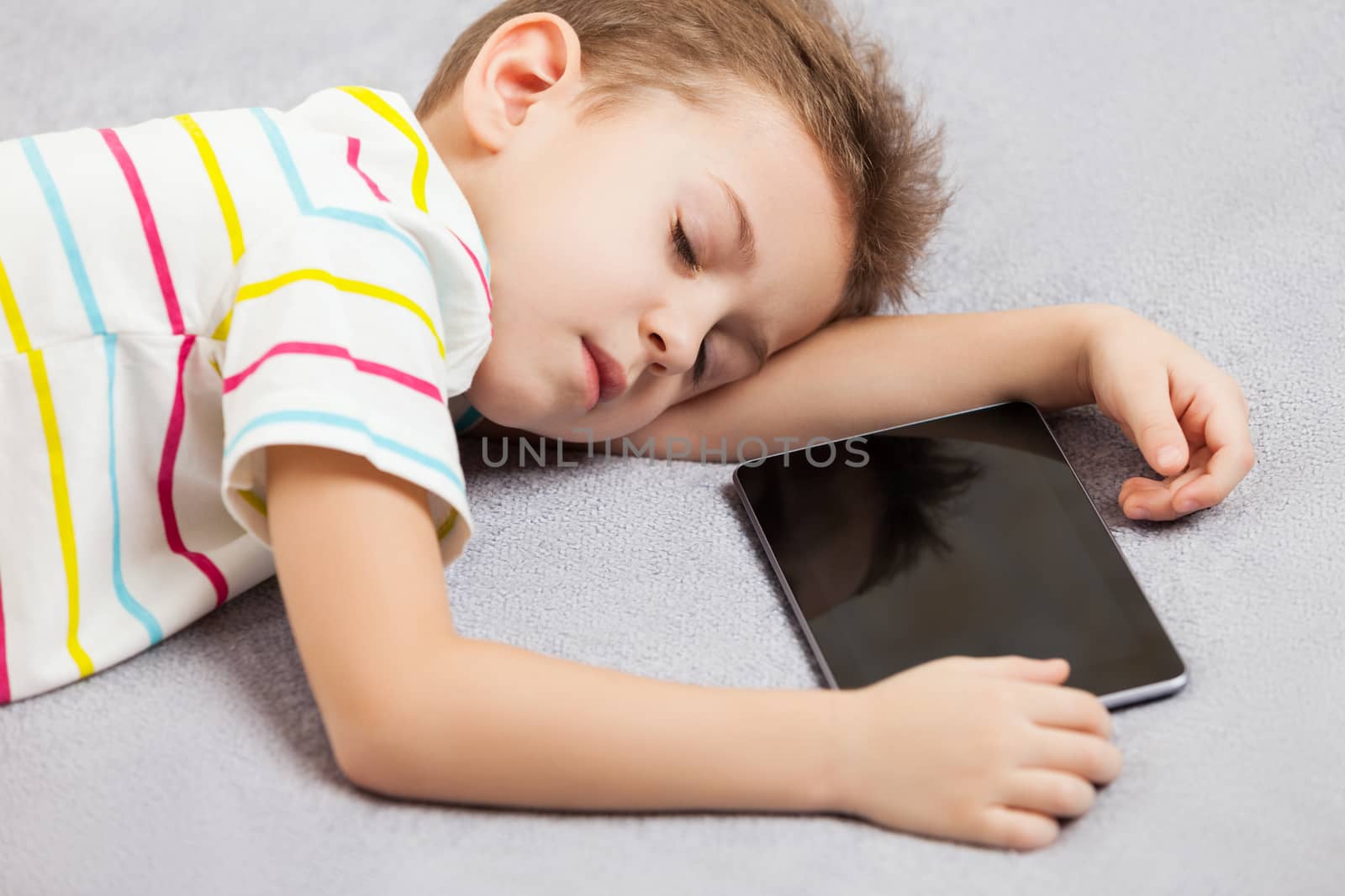 Little tired sleeping child boy hand holding digital tablet computer