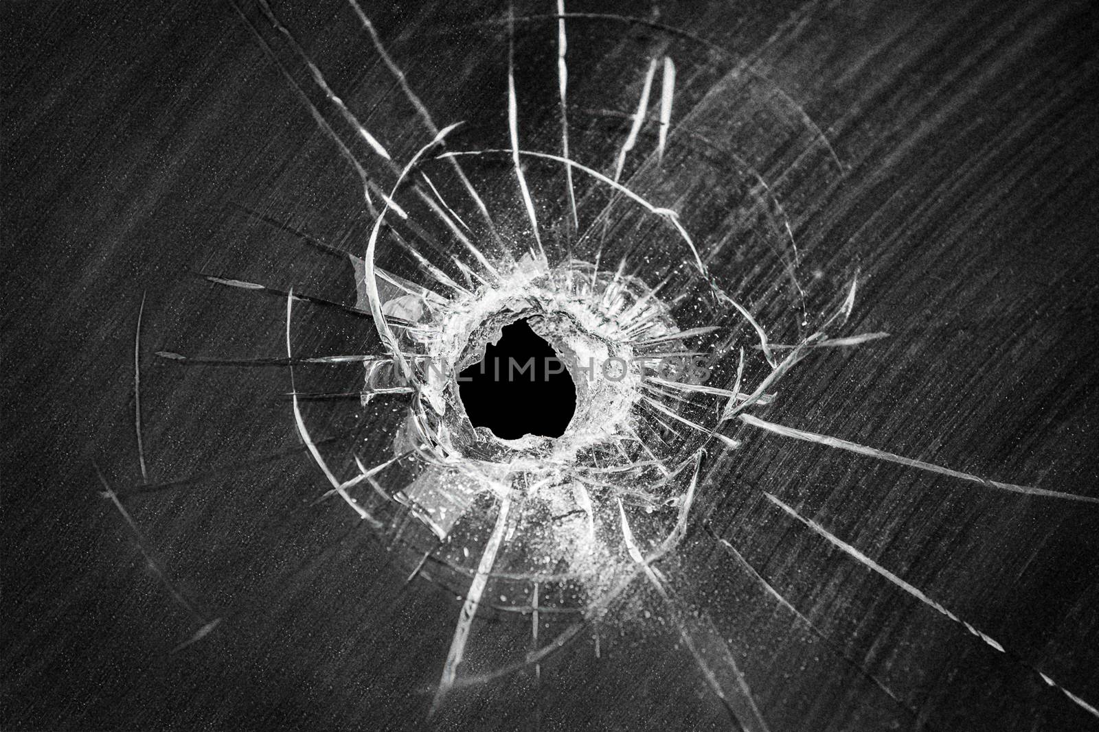 Bullet shot cracked hole on car windshield or accident damaged broken house window glass 
