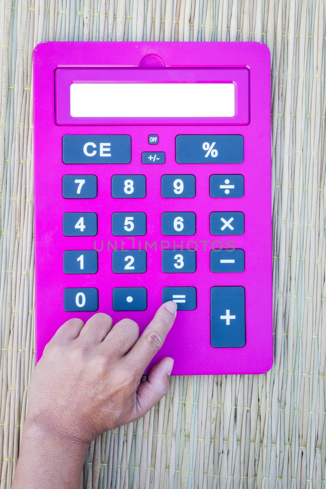 pink calculator on traditional mat with white space on the screen, hand pushing equal button, with white space on the screen