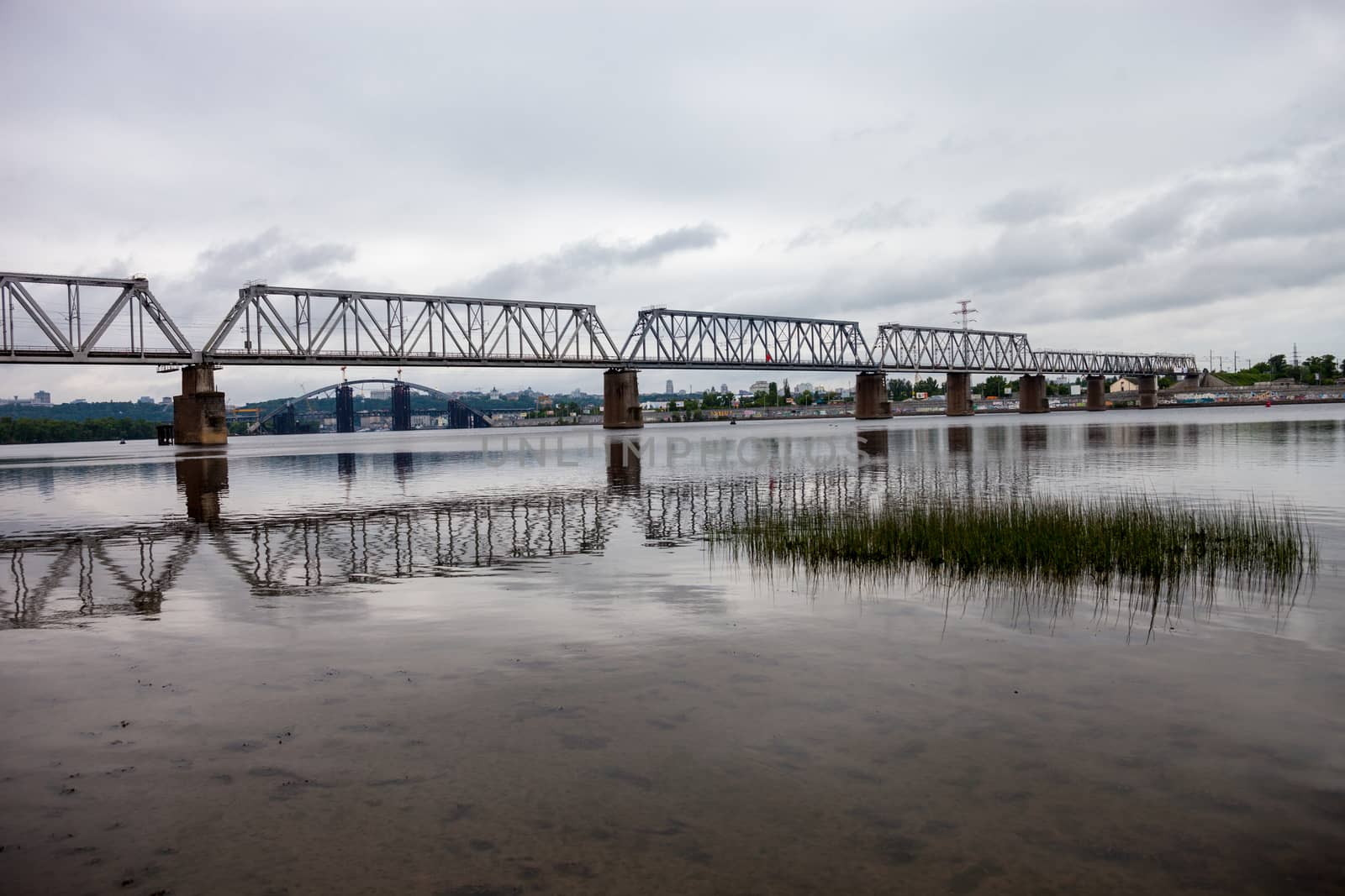 Petrivskiy railroad bridge in Kyiv (Ukraine) across the Dnieper shot from the left bank of the river on the cloudy day,