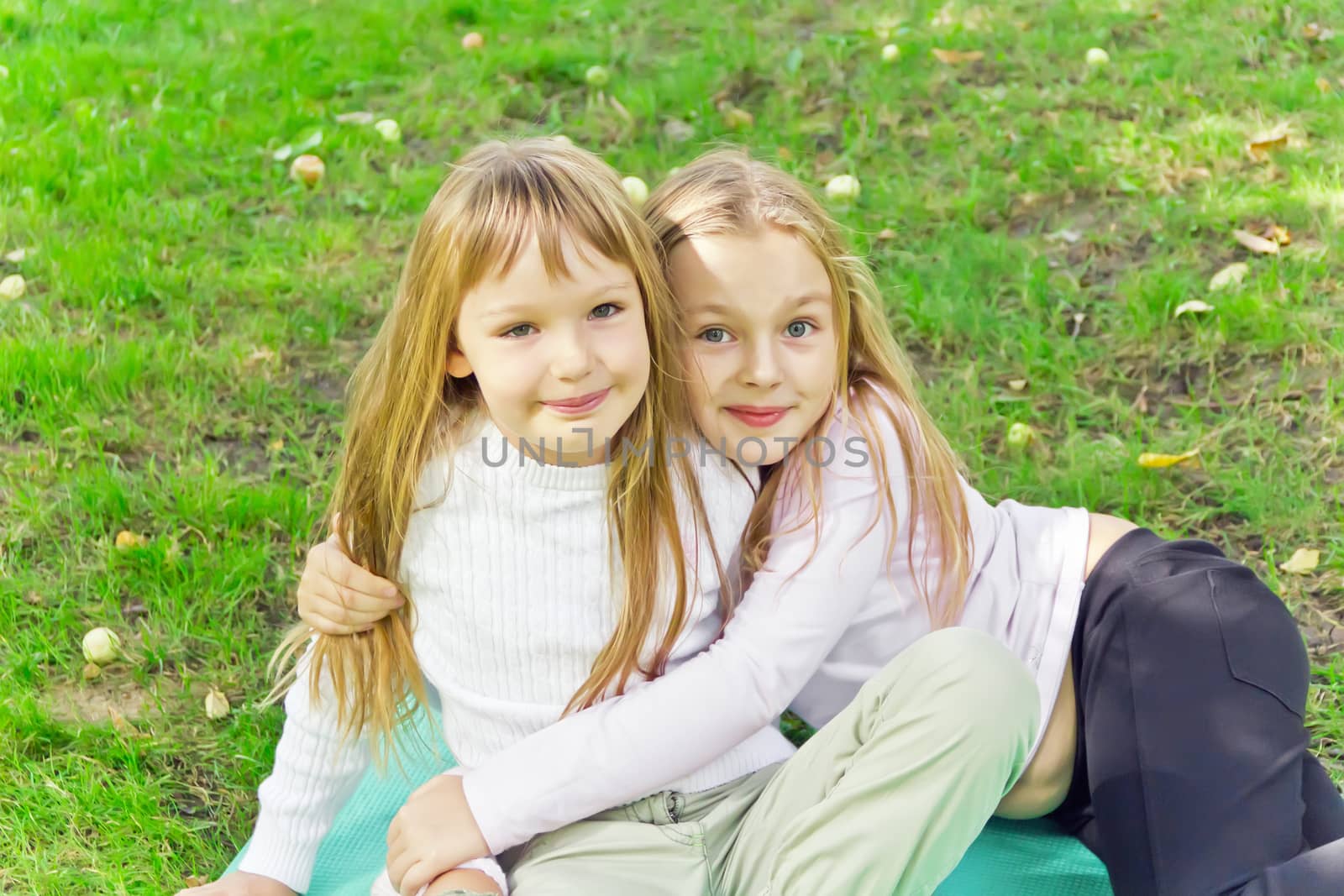 Photo of two girls sitting on grass in summer