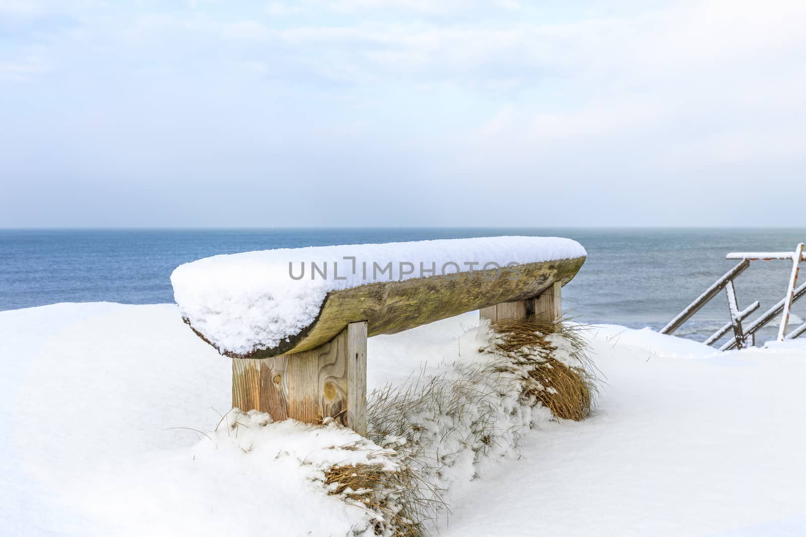 wooden bench covered with snow on the shore of the Baltic Sea, Ventspils, Latvia