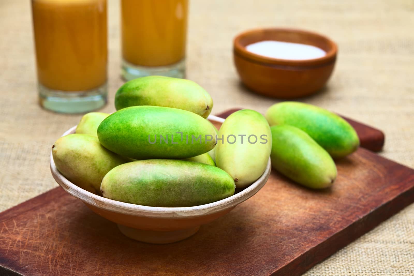 Latin American fruit called banana passionfruit (lat. Passiflora tripartita) (in Spanish mostly tumbo, curuba, taxo) in bowl and banana passionfruit juice in the back (Selective Focus, Focus on the fruits in the front)