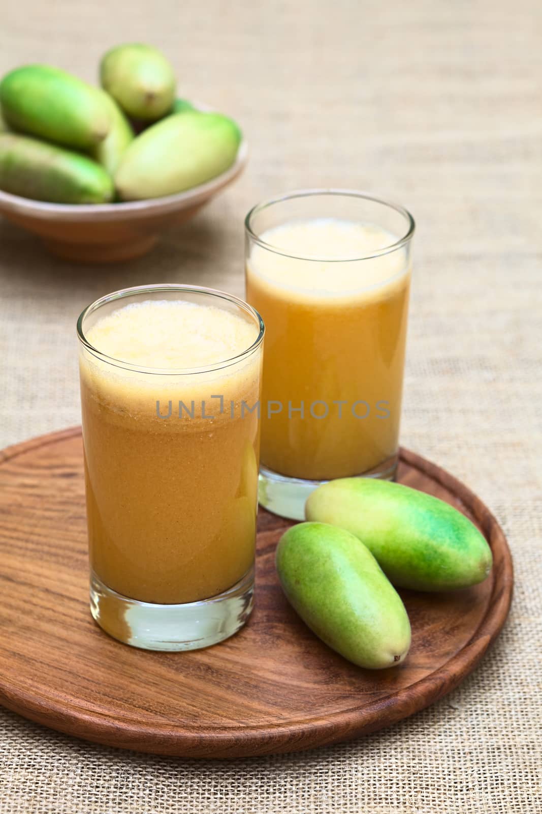 Fresh juice made of the Latin American fruit called banana passionfruit (lat. Passiflora tripartita) (in Spanish mostly tumbo, curuba, taxo) (Selective Focus, Focus on the front of the first glass)