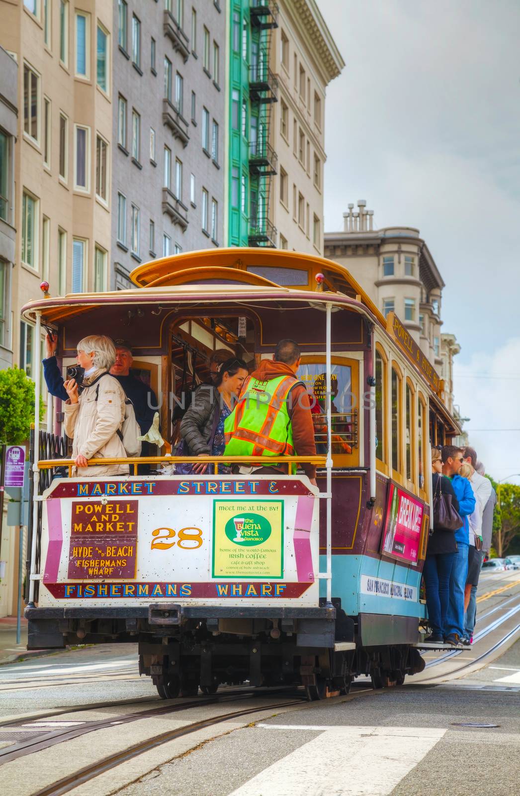 SAN FRANCISCO - APRIL 24: Famous cable car with people at a steep street on April 24, 2014 in San Francisco, California. The cable car system forms part of the intermodal urban transport network.