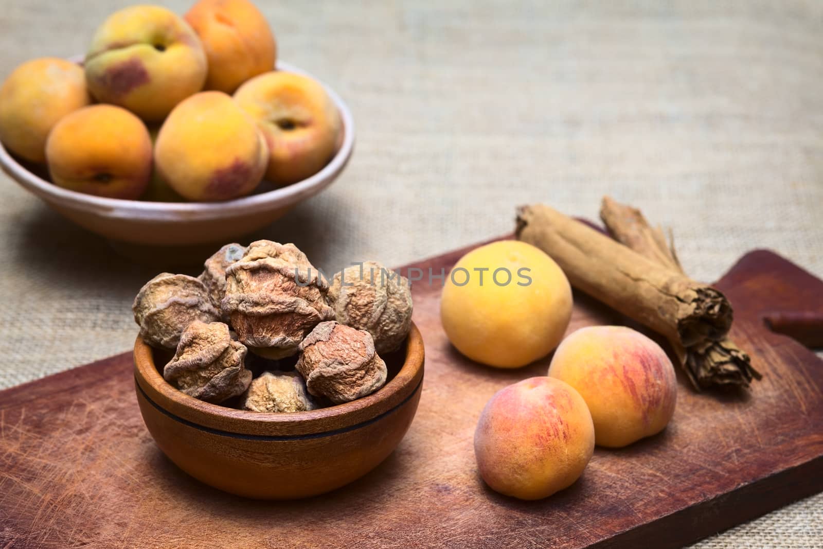 Dried peeled peach called quisa (also kisa, mocochinchi) from which a beverage is prepared with sugar and cinnamon in Bolivia. The drink is very popular and sold on the streets in Bolivia (Photographed with natural light) (Selective Focus, Focus on the front peaches)
 