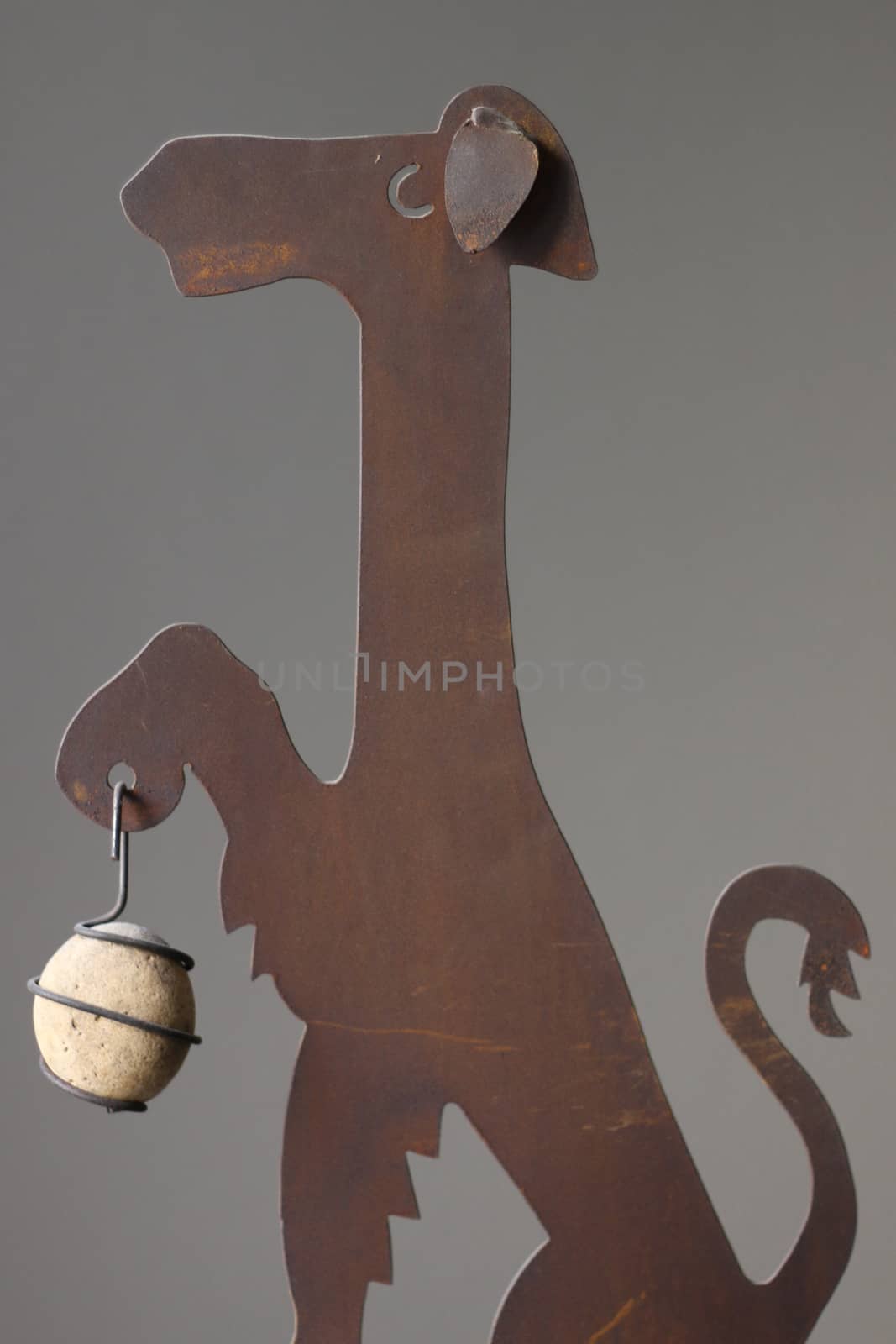 Metal Dog Holding Rock on Gray Background