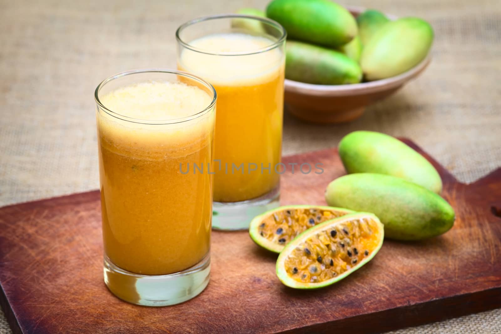 Fresh juice made of the Latin American fruit called banana passionfruit (lat. Passiflora tripartita) (in Spanish mostly tumbo, curuba, taxo) (Selective Focus, Focus on the front of the first glass)