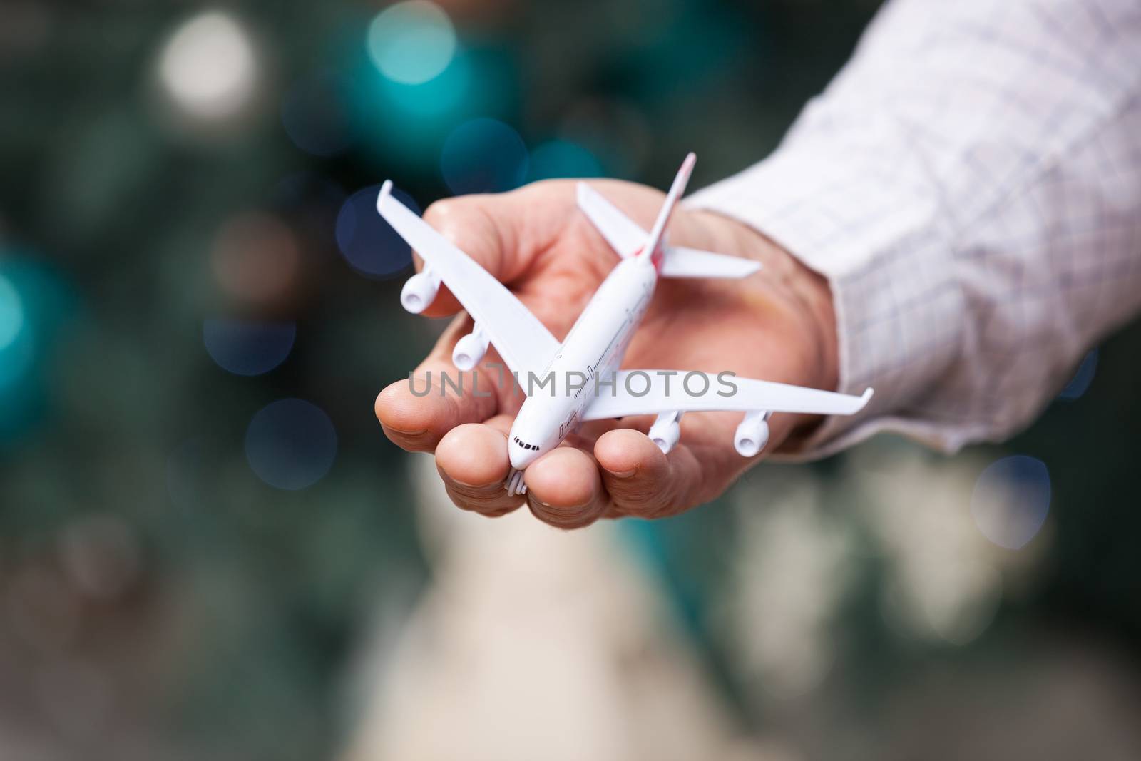 Closeup of man hand holding model of airplane over christmas background