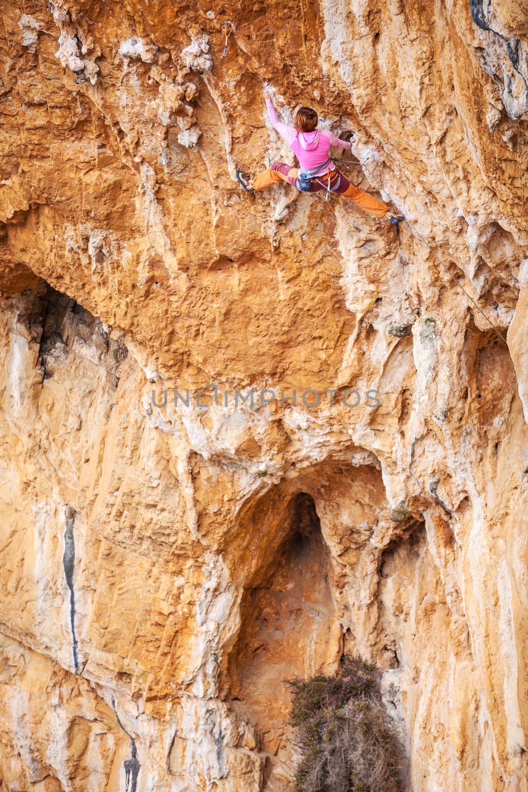 Young female rock climber on a cliff by photobac