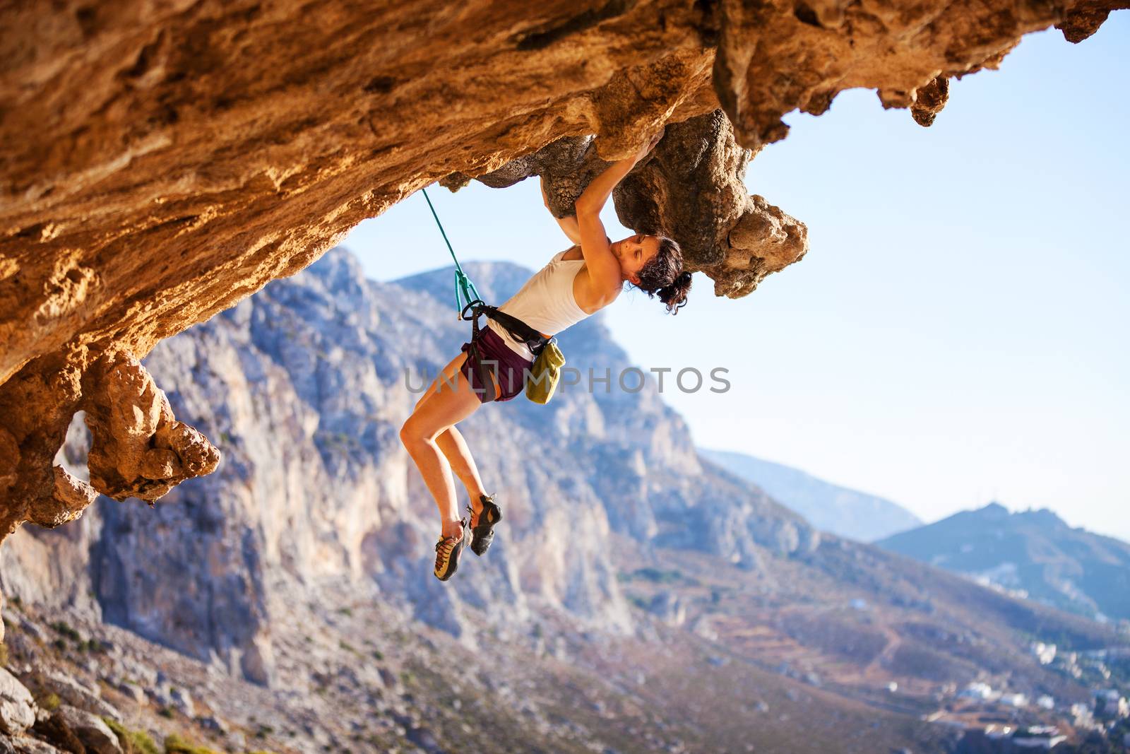 Young female rock climber on a face of cliff