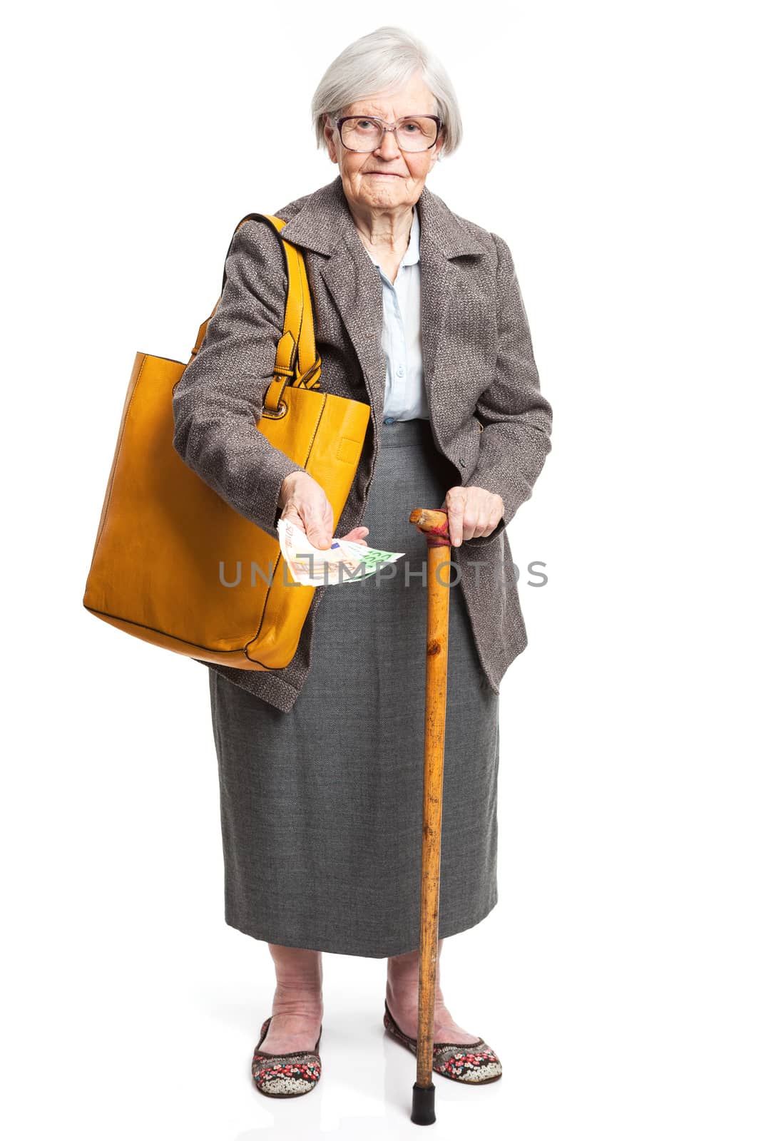 Senior woman holding money while standing over white background