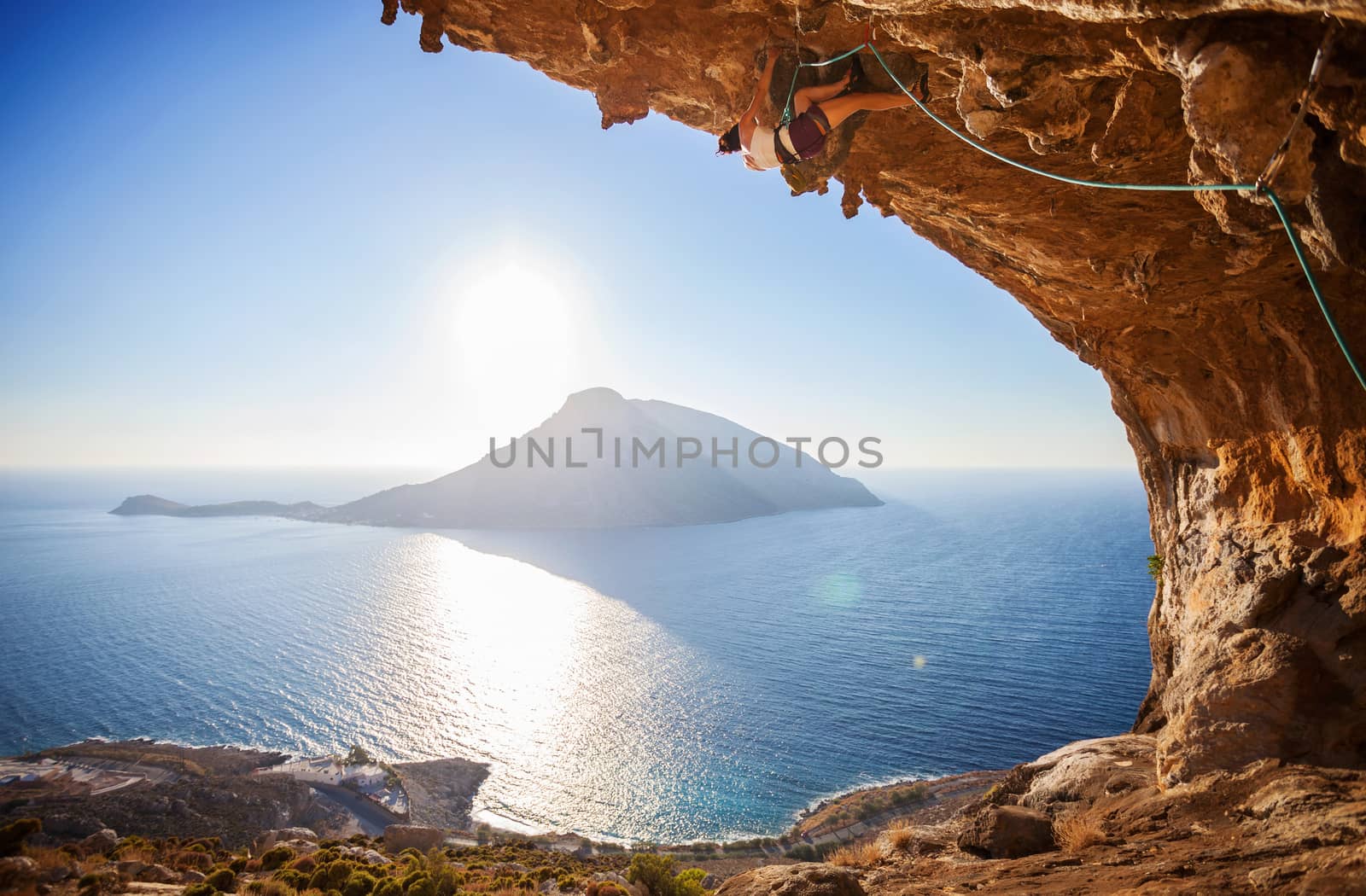 Male rock climber climbing along a roof in a cave by photobac