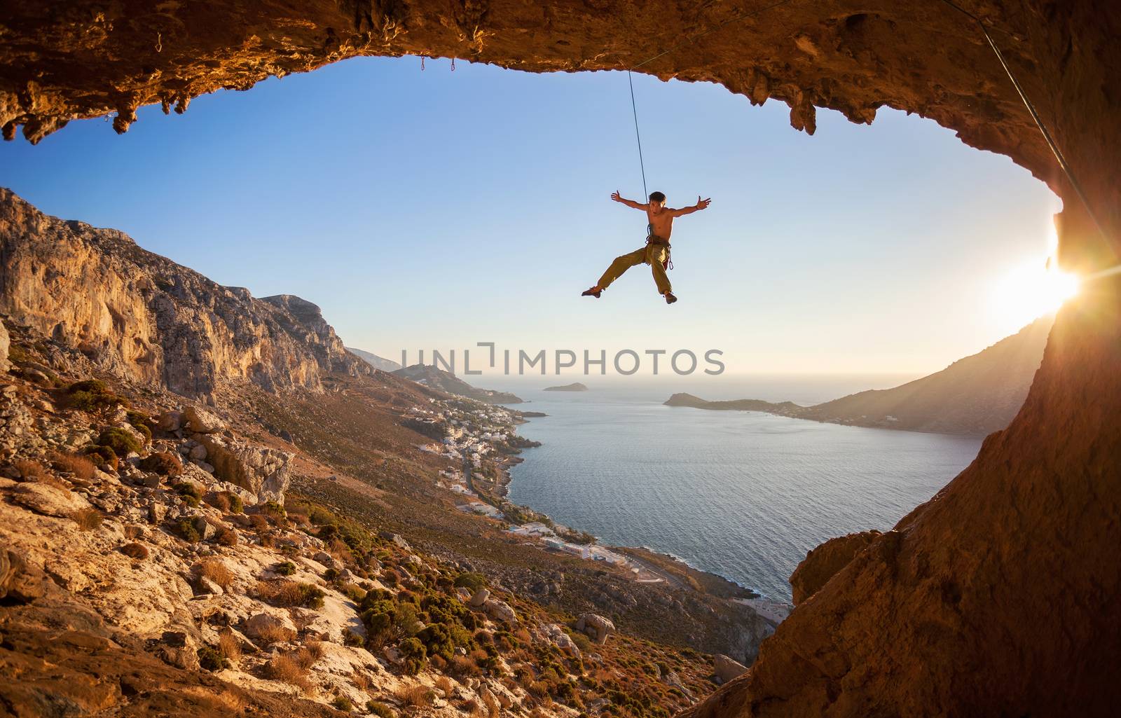 Rock climber hanging on rope while lead climbing by photobac