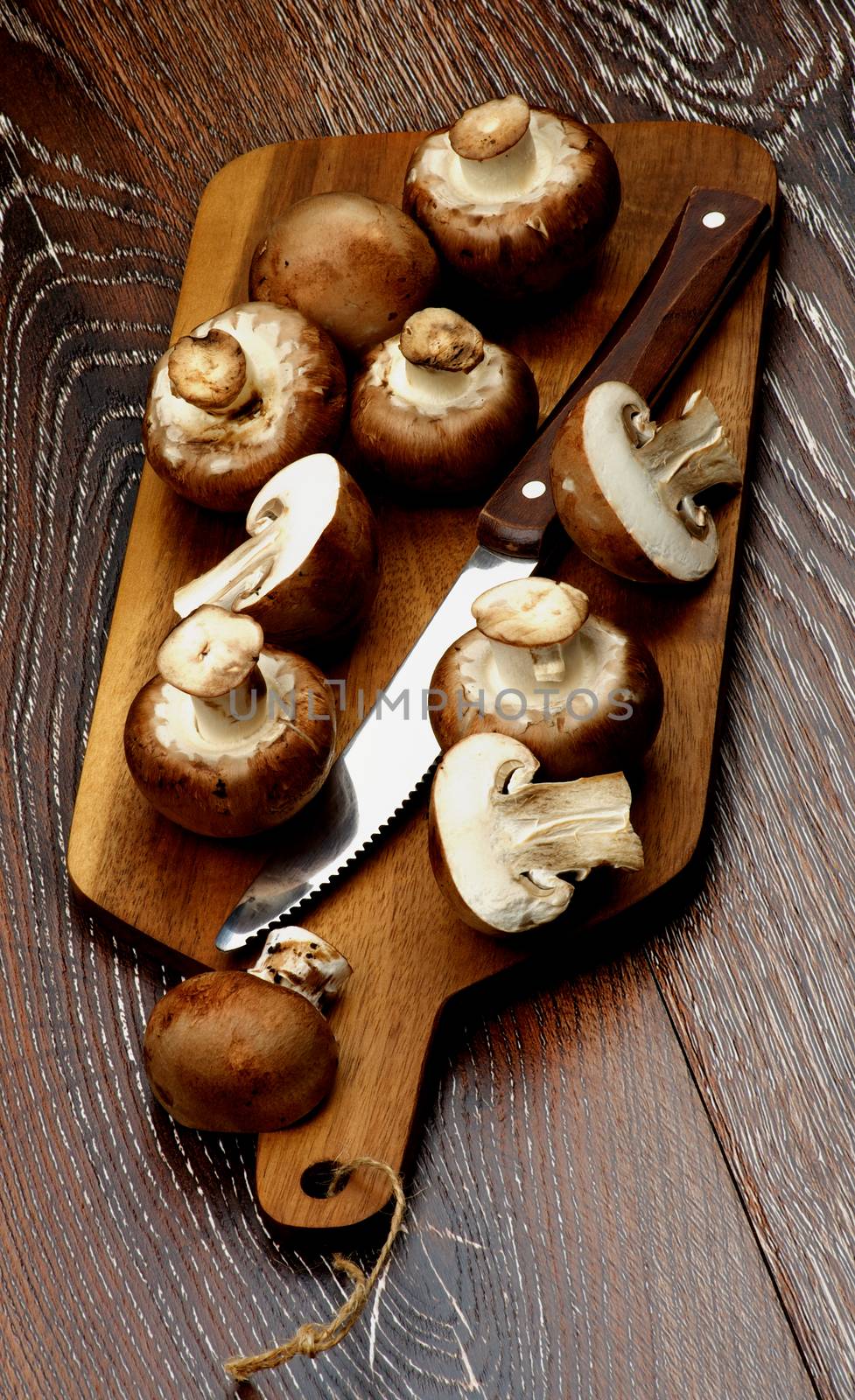 Gourmet Raw Portabello Mushrooms Full Body and Halves with Table Knife on Cutting Board closeup on Dark Wooden background