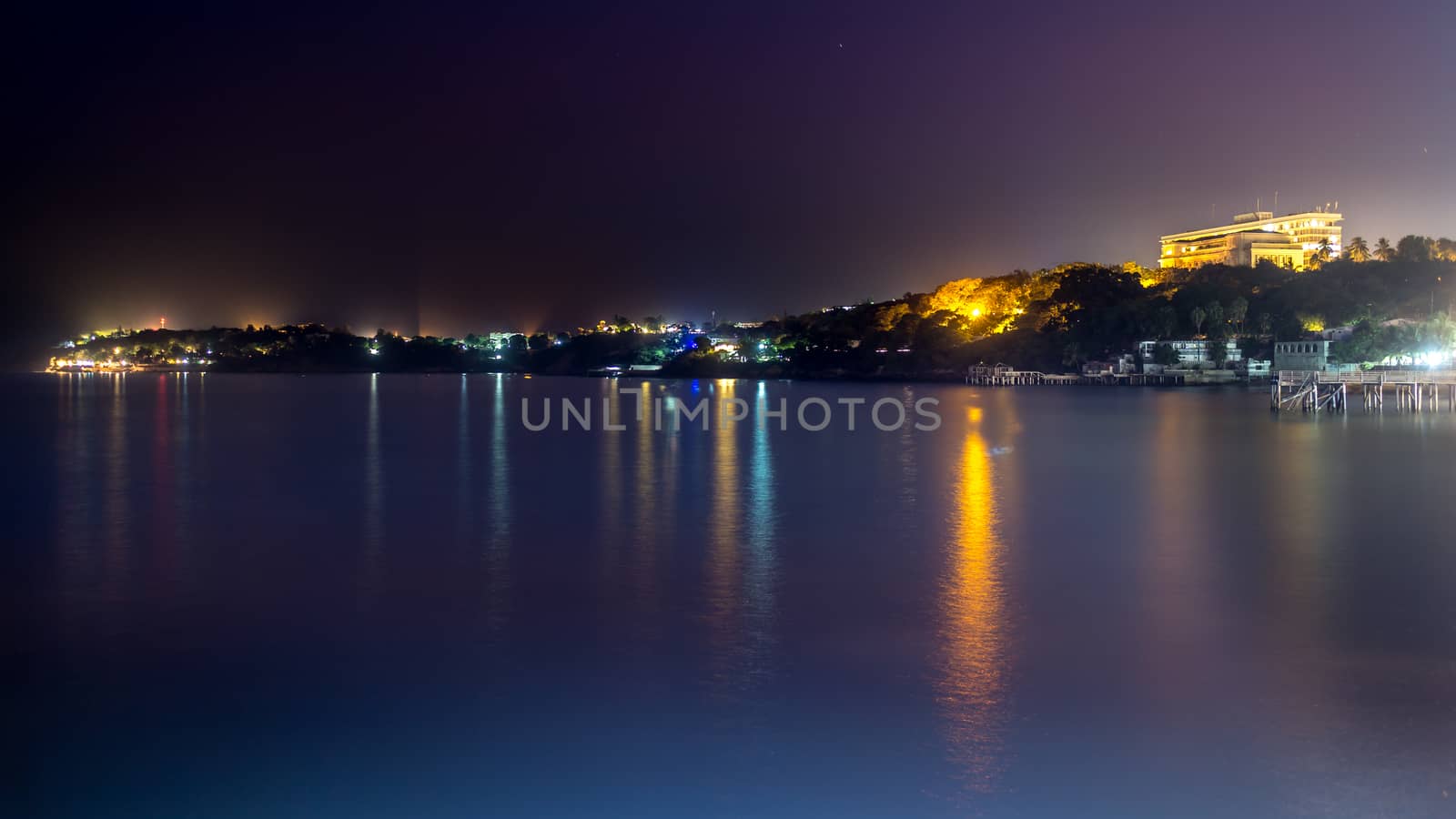 The still waters of the Atlantic ocean reflecting the colourful lights along the shores of downtown Dakar