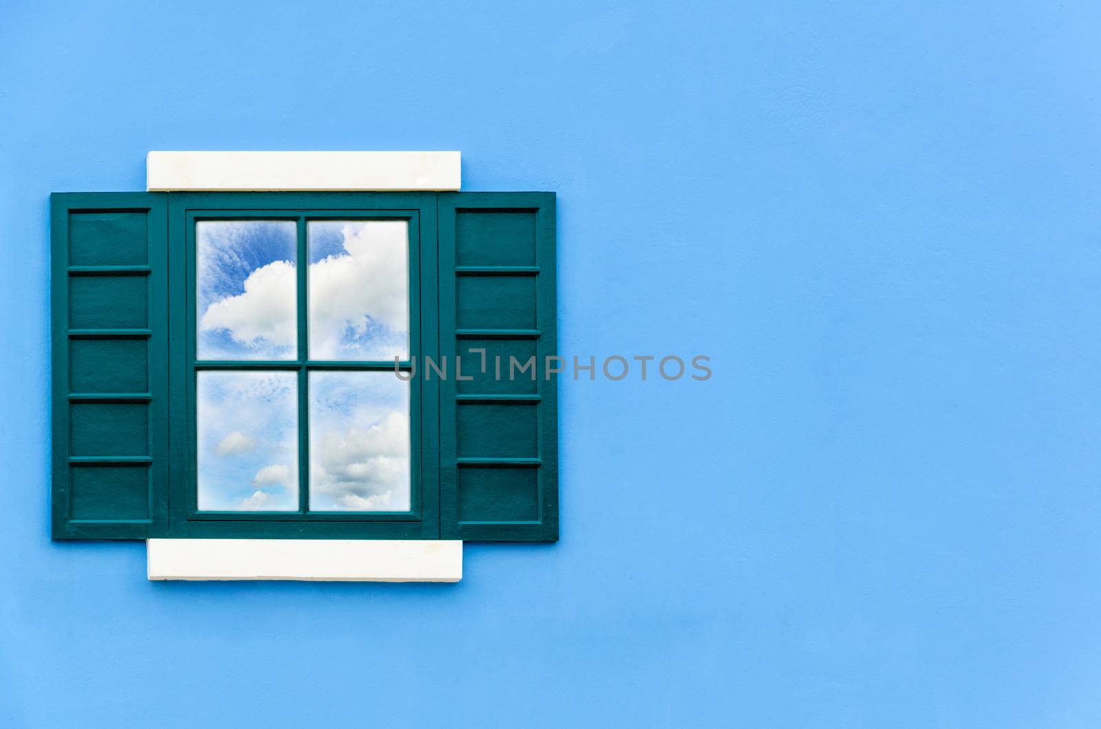 Sky and cloud reflection in green window glass on blue wall of house, Italy retro style