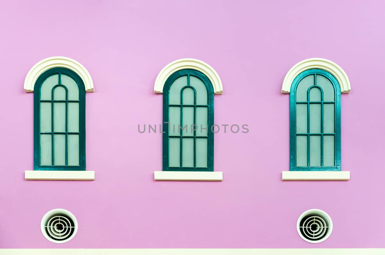 Three green arched windows on pink wall of the house in Italy retro style