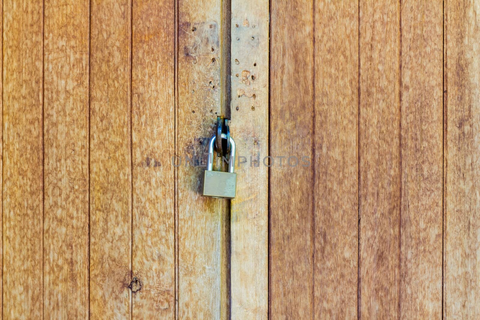 Old wooden doors are locked with a padlock, with copyspace