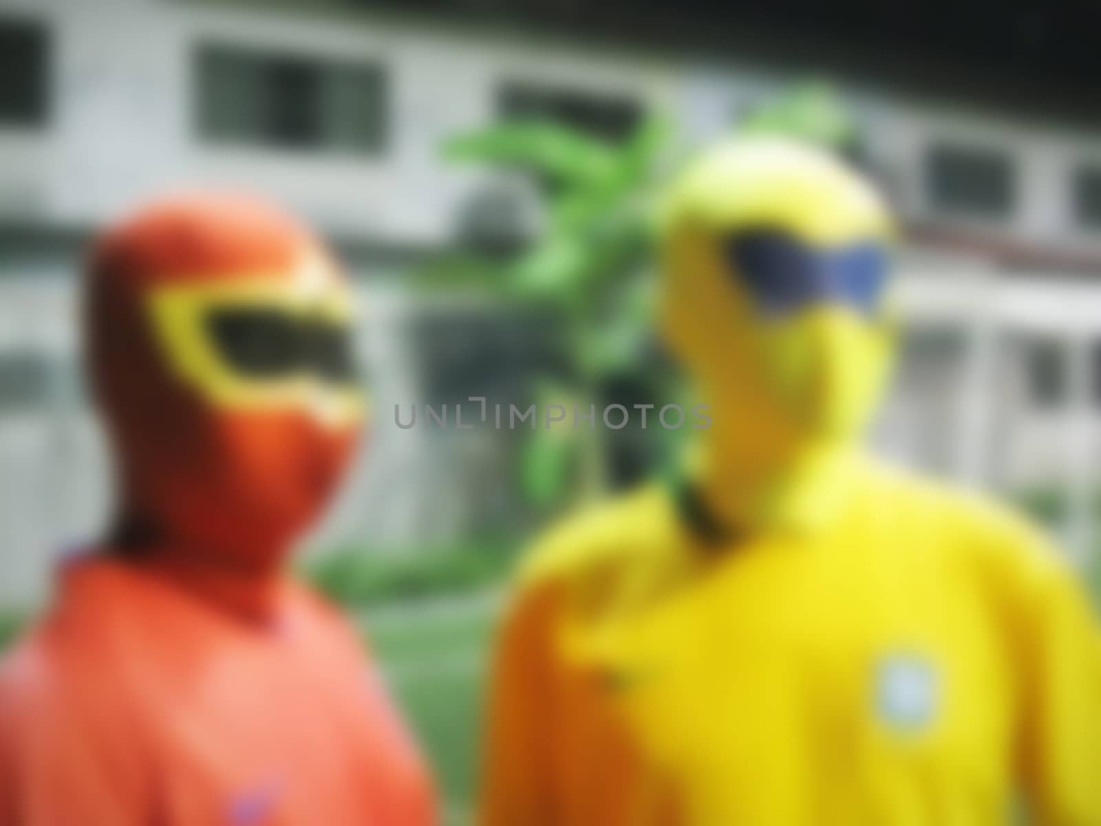 defocused of two men with masks in red and yellow cloths by a3701027