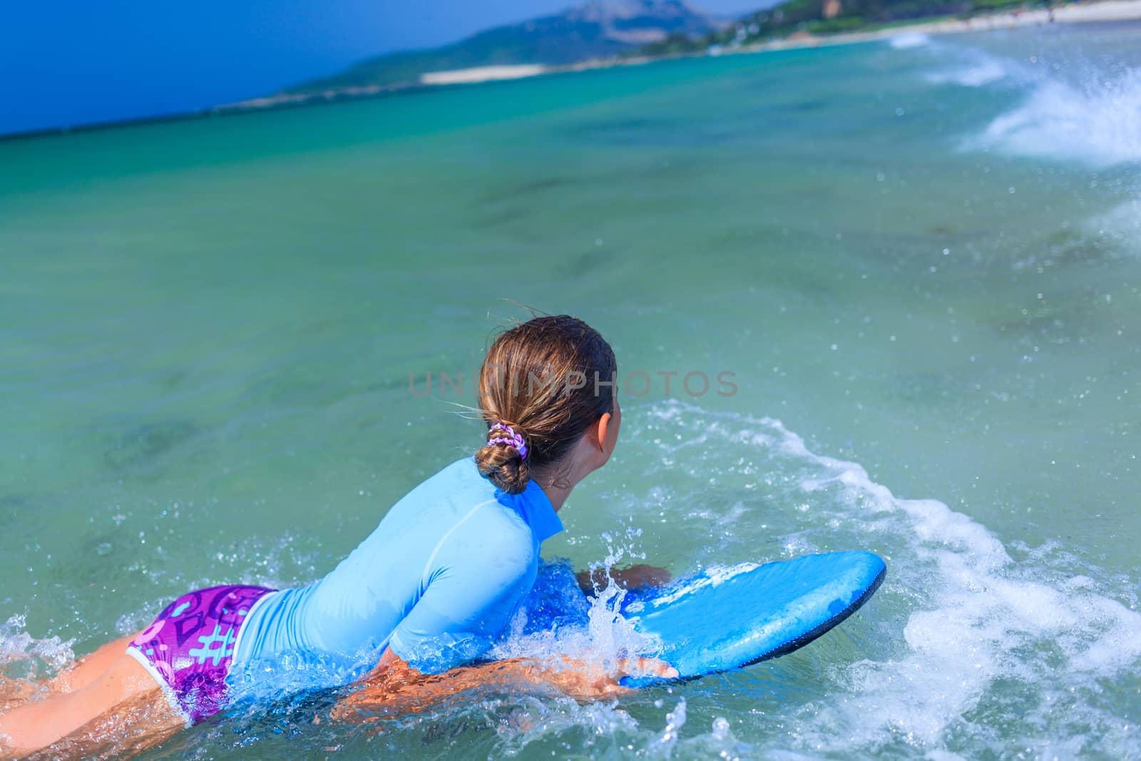Teenage girl in blue has fun surfing