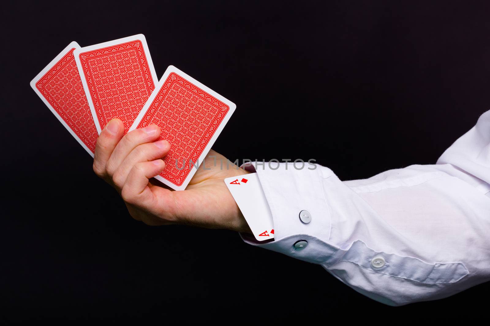 On a black background man's hand holding three cards and the ace in the hole