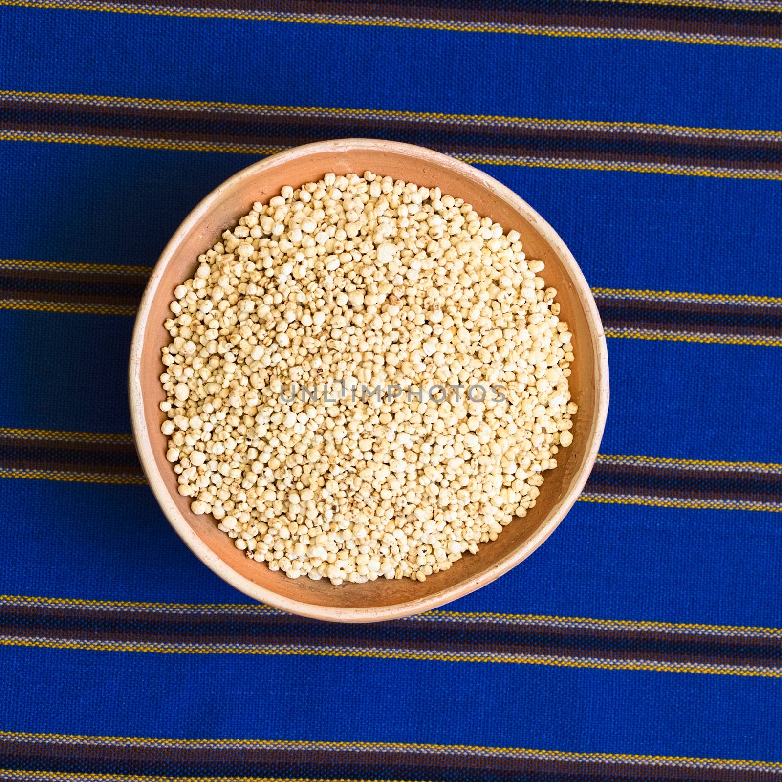 Popped quinoa cereal in clay bowl on blue striped fabric, photographed with natural light 