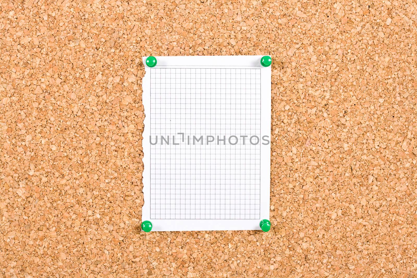Photo of a piece of squared paper taken out of a notebook, the paper is pinned to a cork board, the photo is ideal as background for informations.