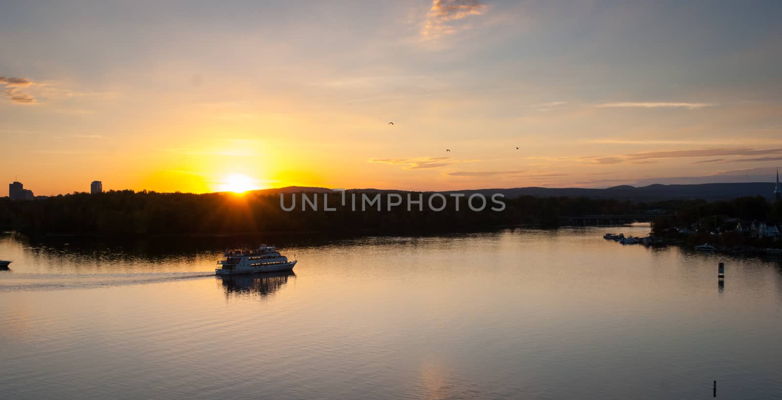 A riverboat of sight-seers cruise the river on a lovely warm summer evening