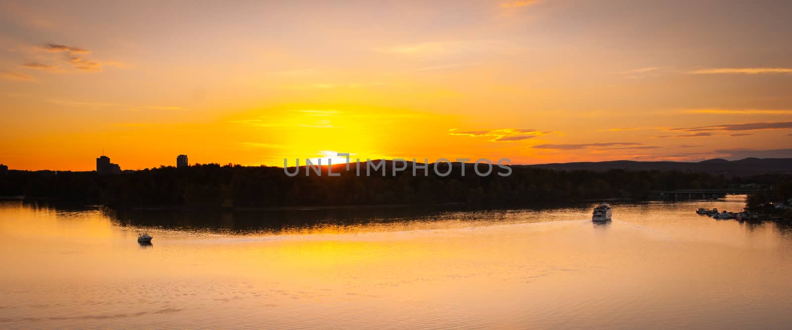 A riverboat of sight-seers cruise the river on a lovely warm summer evening