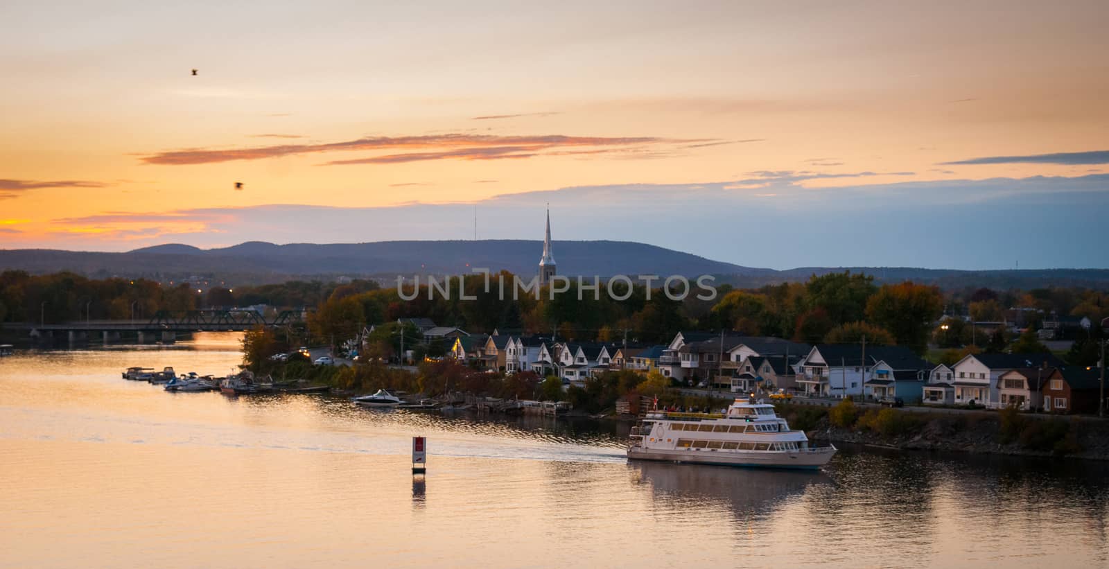 A riverboat of sight-seers cruise the river on a lovely warm summer evening