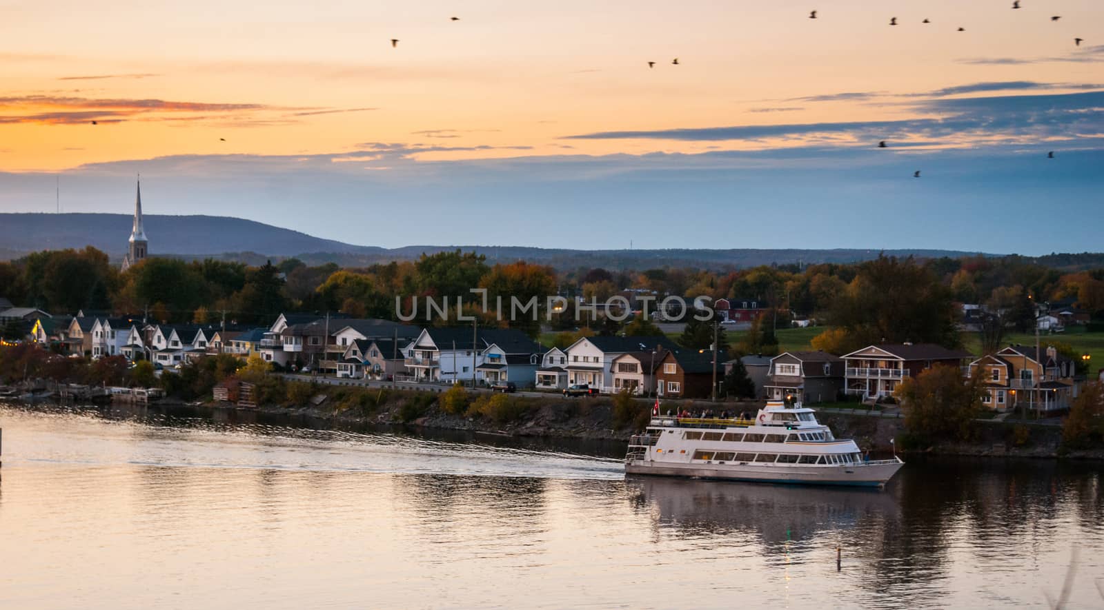 A riverboat of sight-seers cruise the river on a lovely warm summer evening