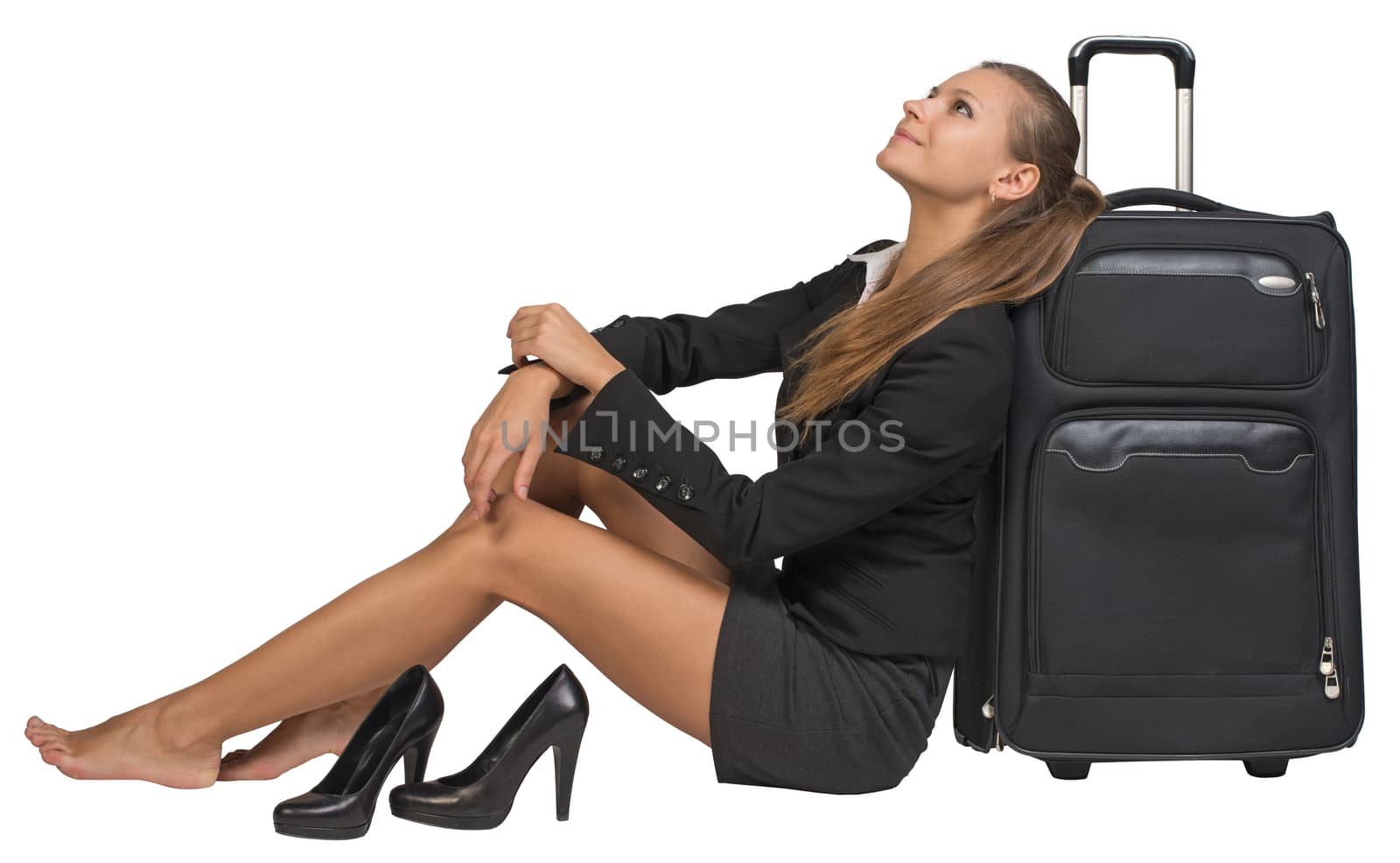 Businesswoman with her shoes off sitting next to front view suitcase with extended handle, looking upwards. Isolated over white background