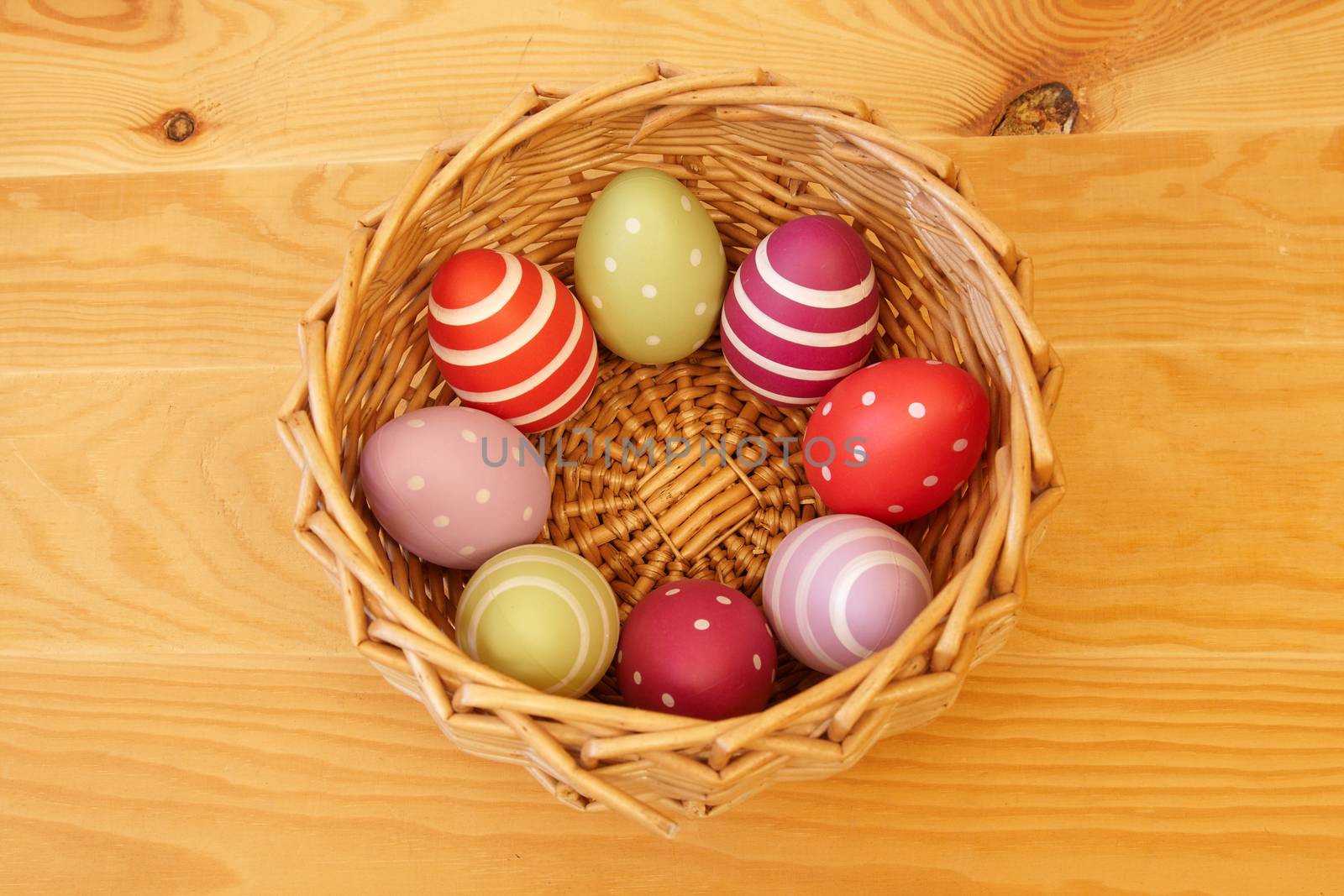 Eight colored easter eggs in the basket on the wooden background