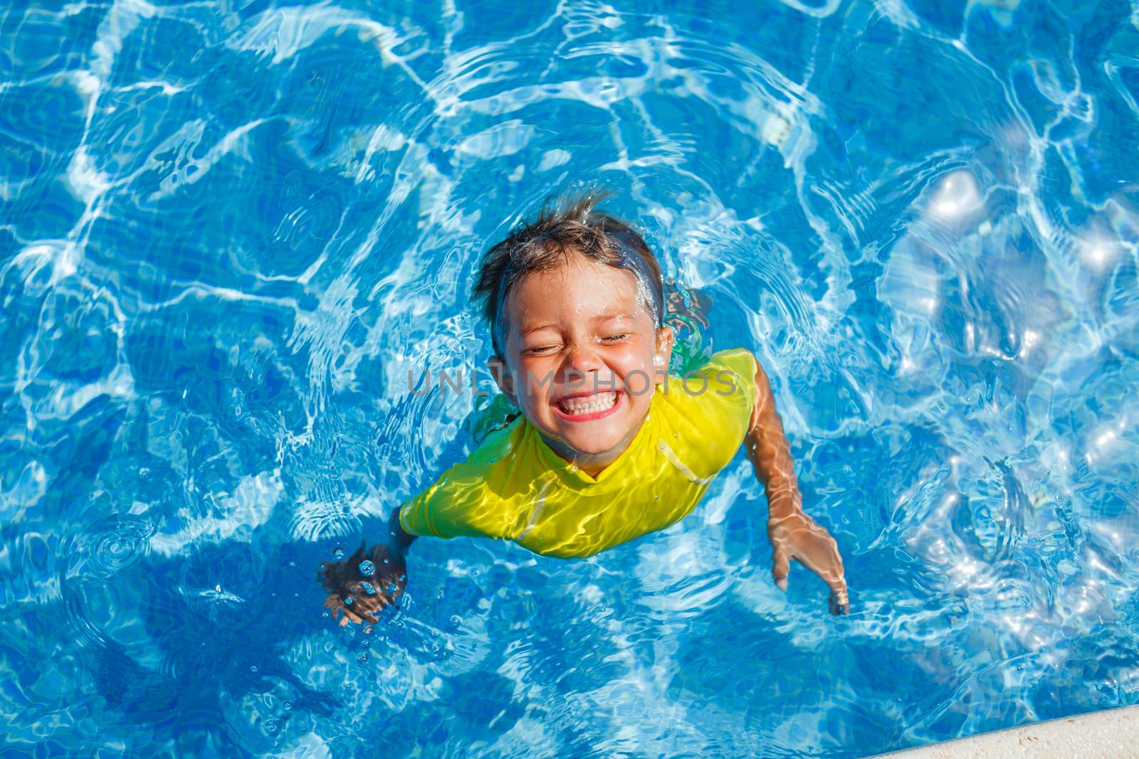 Cute happy little boy swimming and snorking in the swimming pool