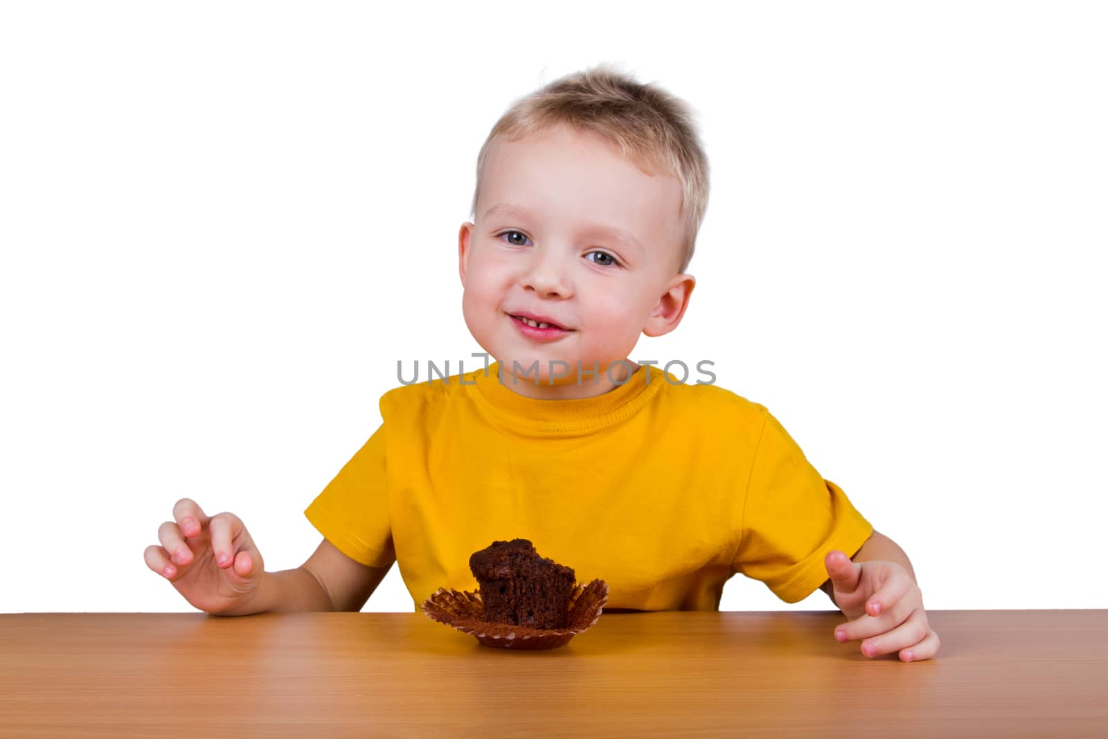 A small boy in yellow t-shirt eating a chocolate muffin. Isolated on white background