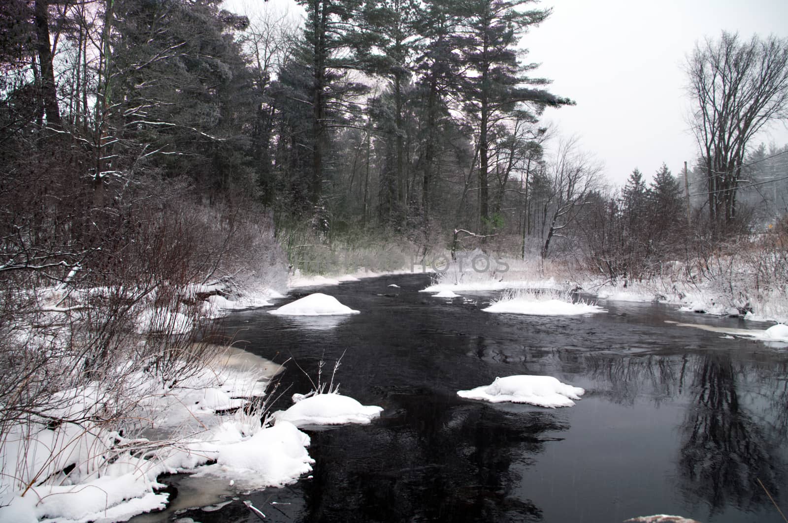Winter stream flowing open in extreme cold with frost