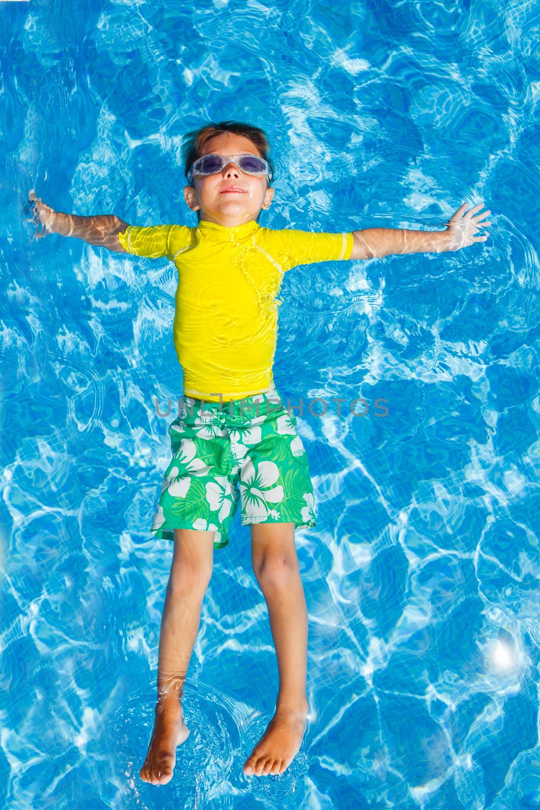 Cute happy little boy in goggles swimming and snorking in the swimming pool