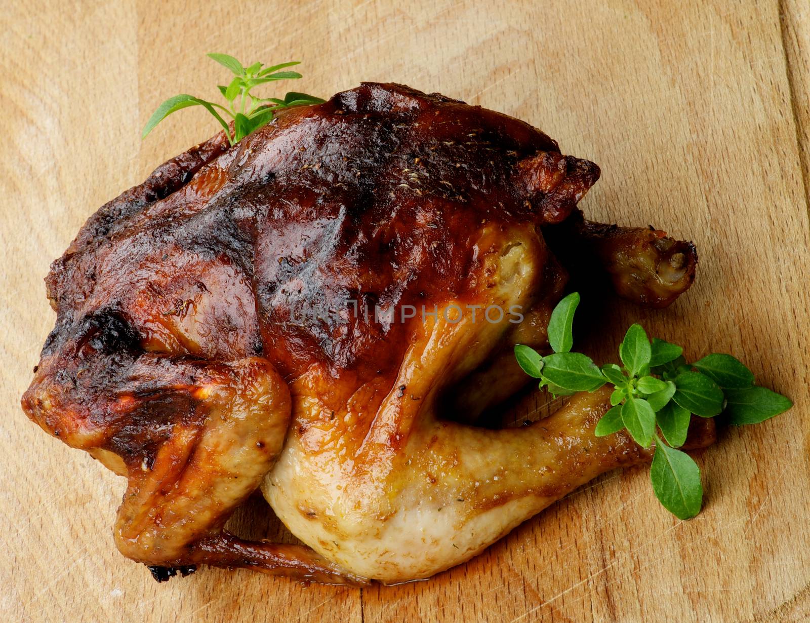 Roasted Chicken Full Body with Fresh Basil Leafs closeup on Wooden Cutting Board