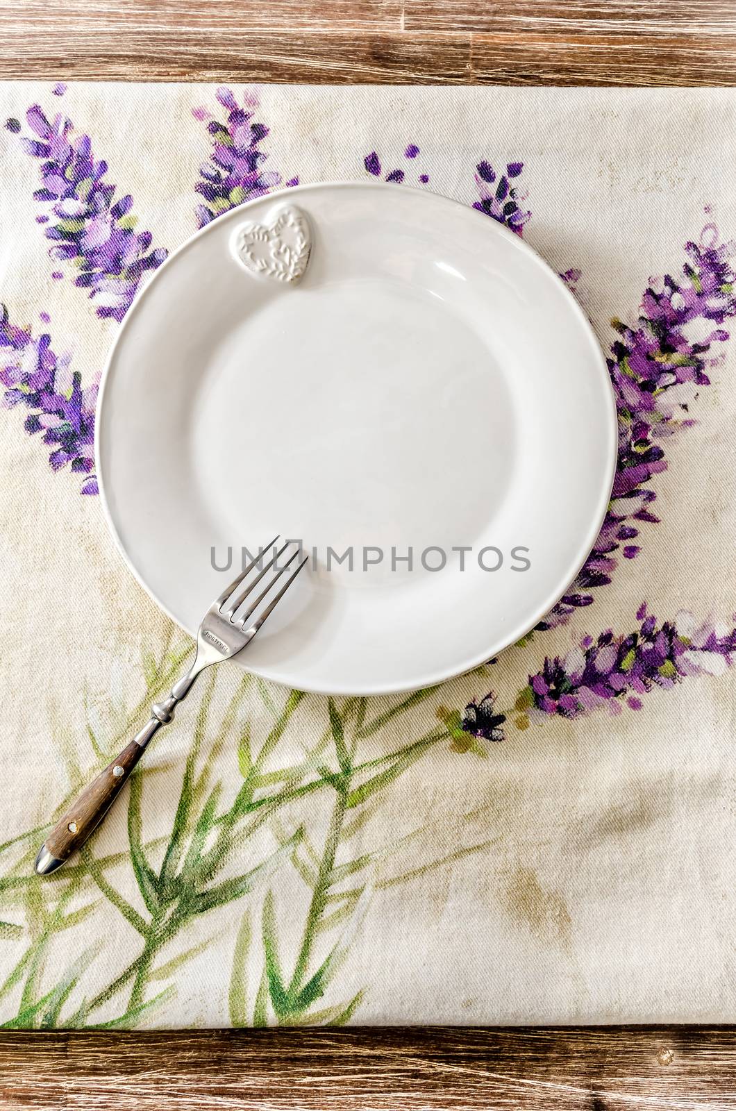 Plate and fork on vintage wooden dining table with colorful tablecloth