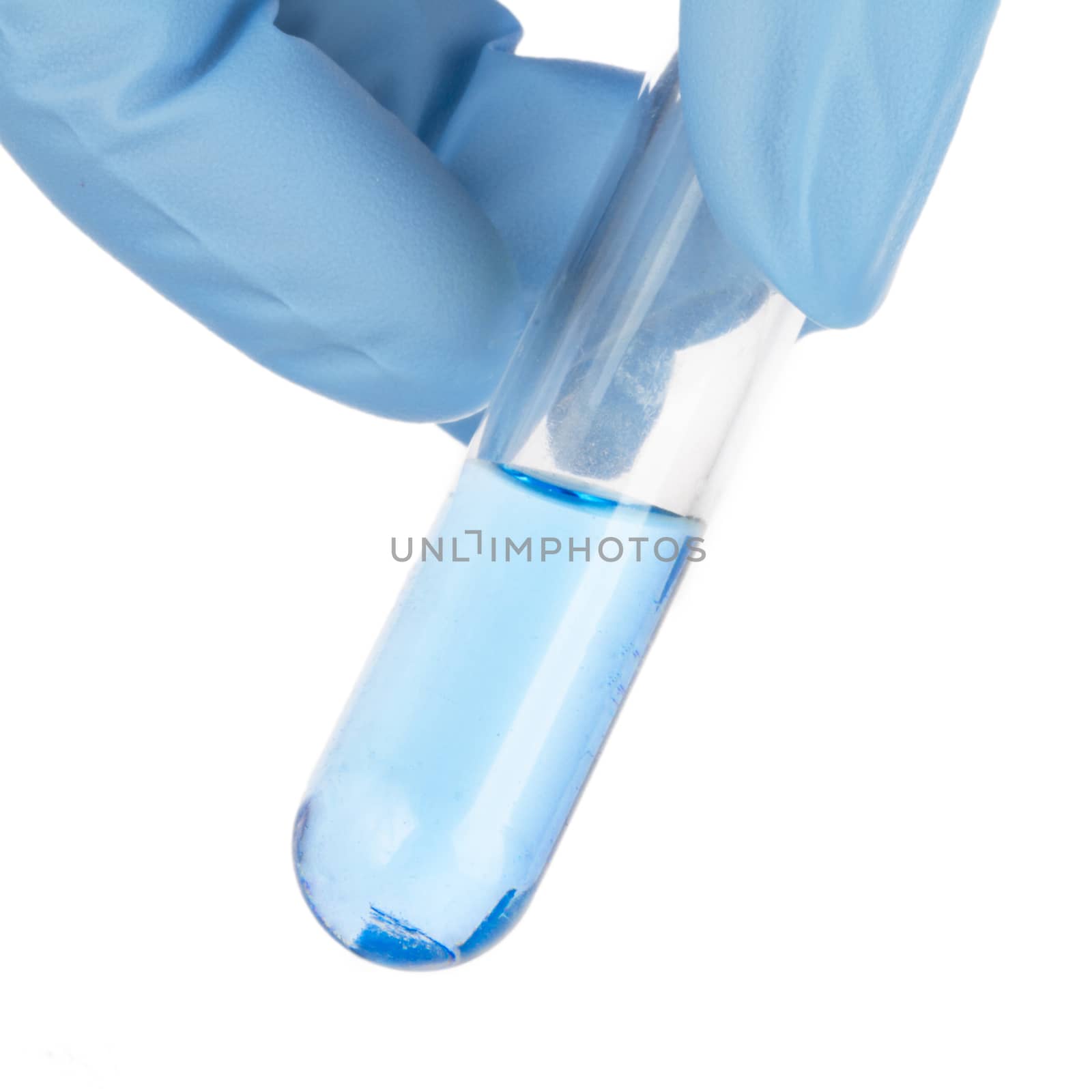 Fingers holding test tube with blue liquid.