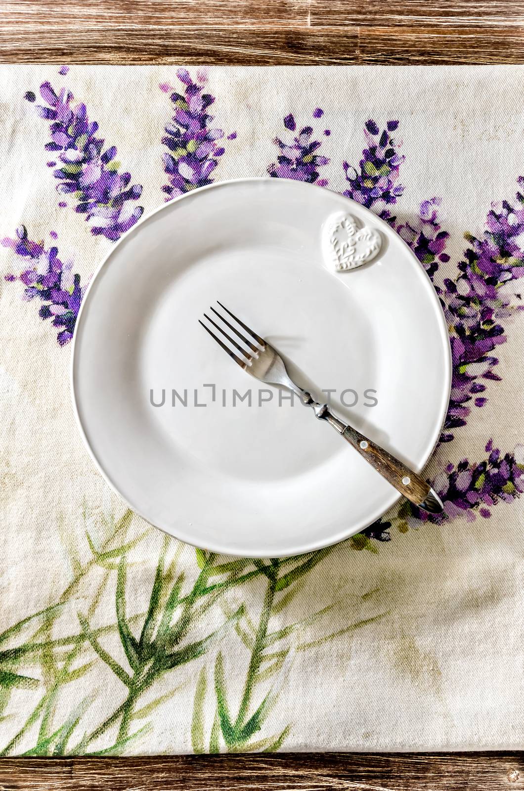 Plate and fork on vintage wooden dining table with colorful tablecloth