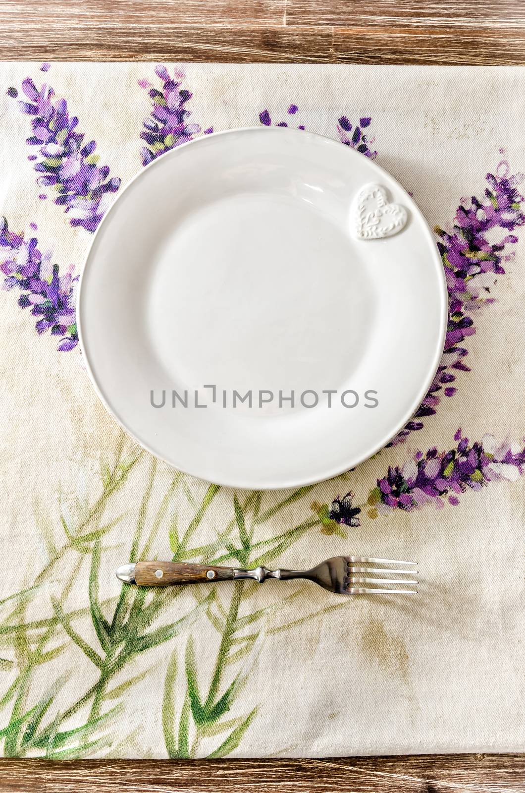 Plate and fork on vintage wooden dining table with colorful tablecloth