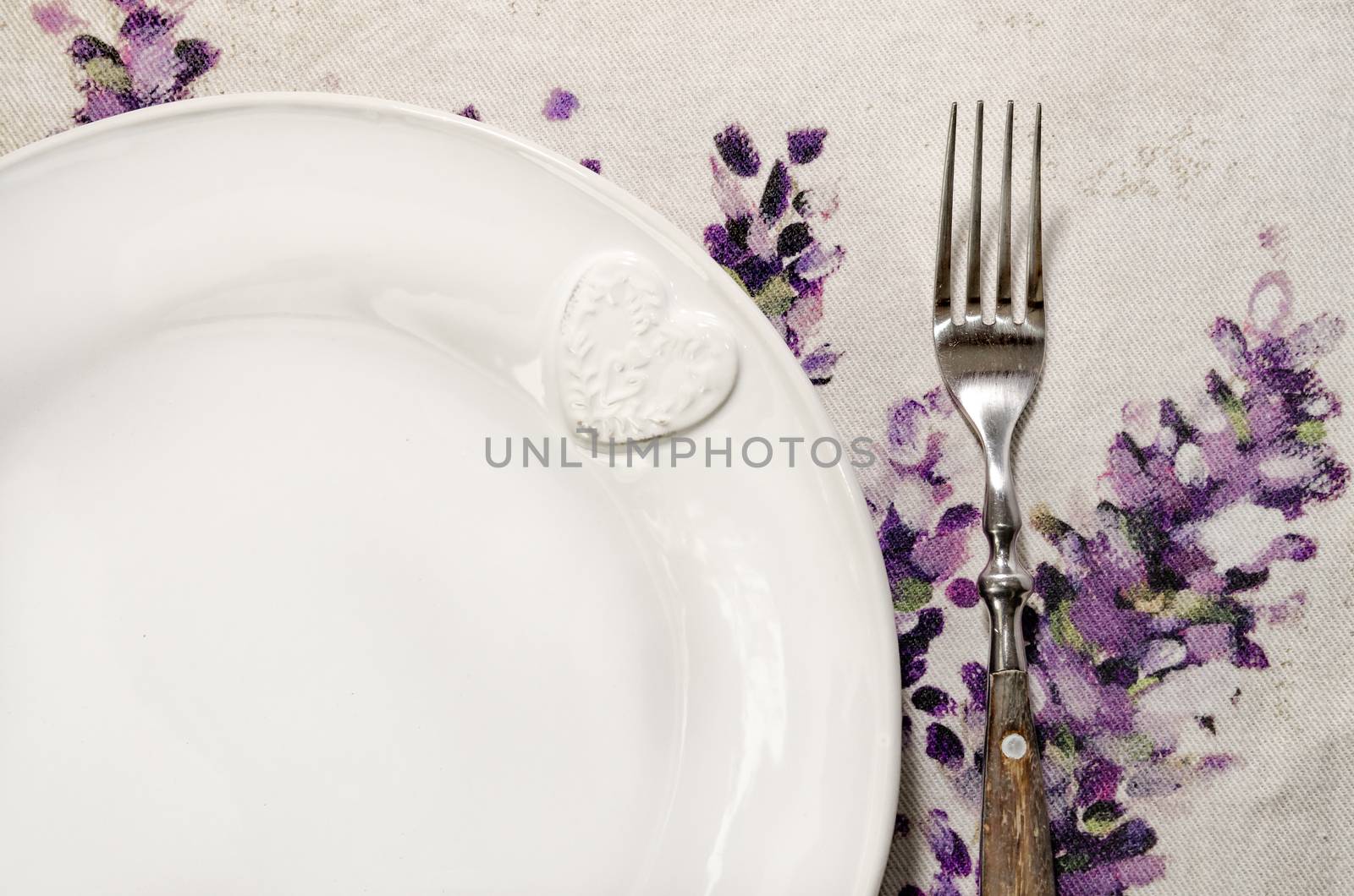 Detail of plate and fork laid on vintage wooden dining table  by martinm303