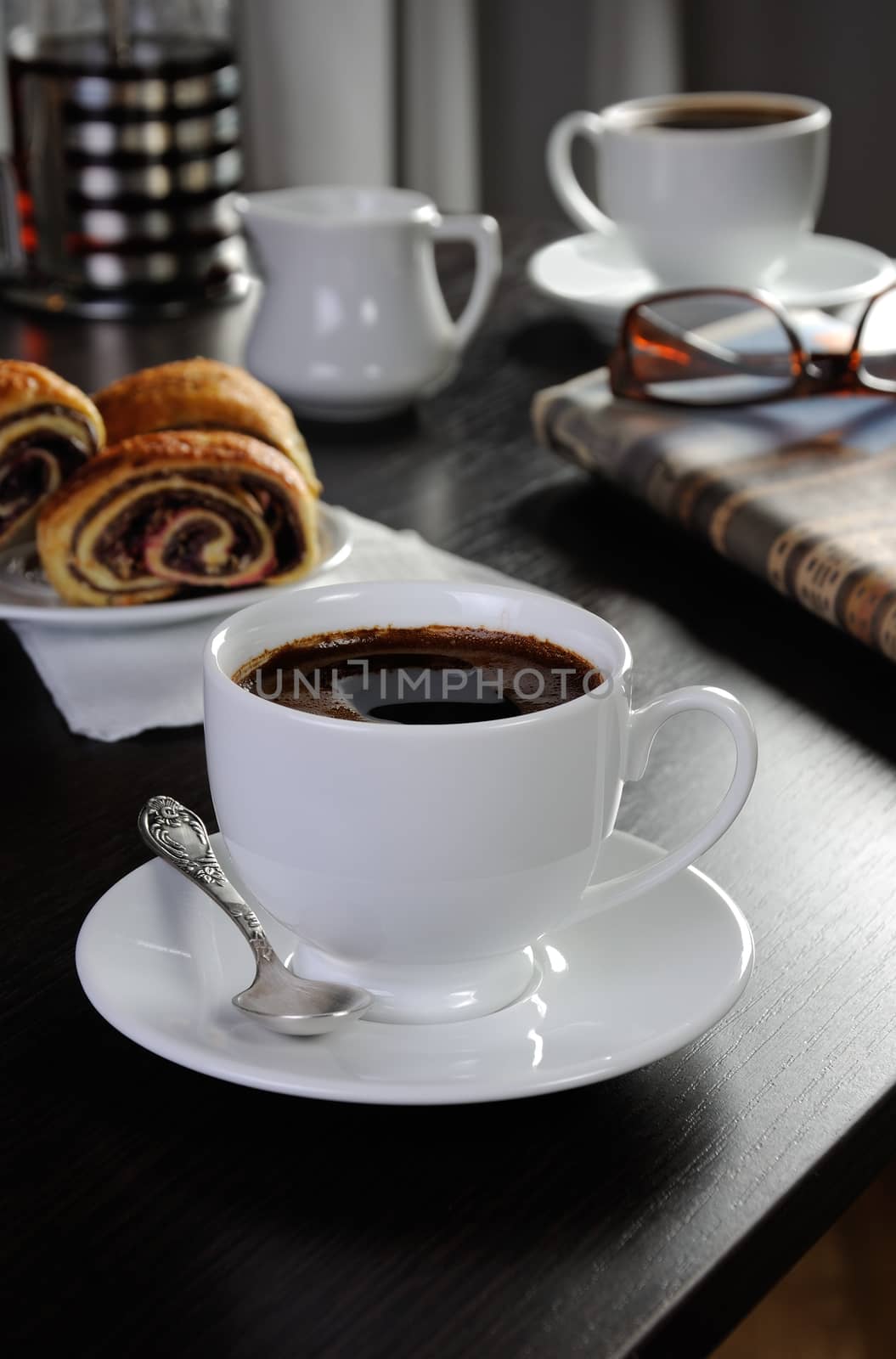 cup of coffee on the table with bread rolls and newspapers