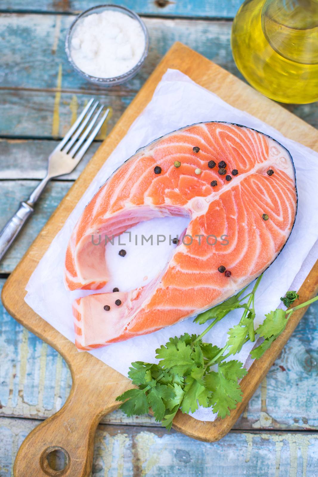 piece of raw red fish with parsley, pepper and olive oil