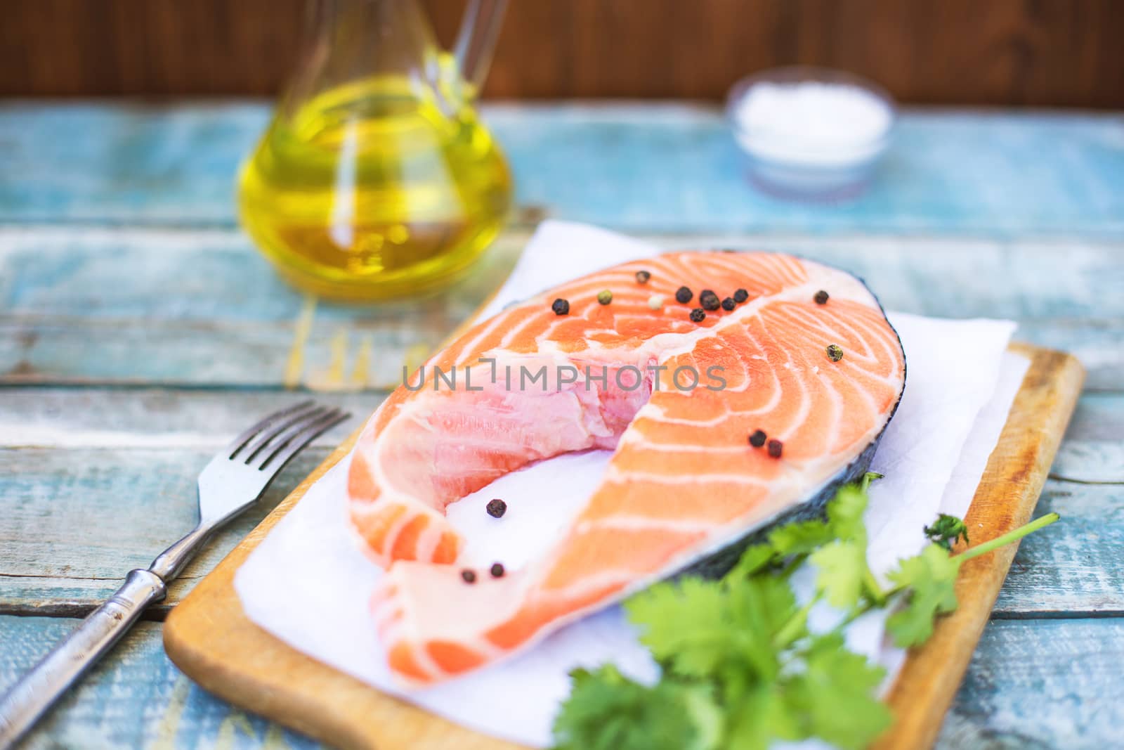 piece of raw red fish with parsley, pepper and olive oil