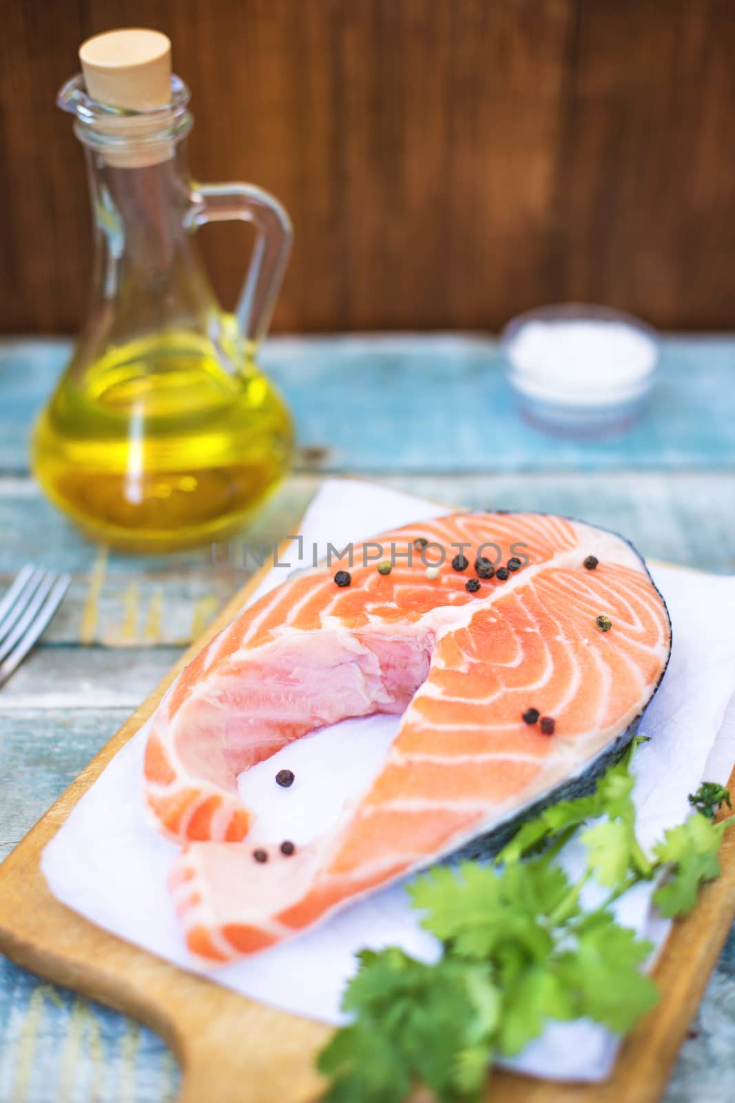 piece of raw red fish with parsley, pepper and olive oil