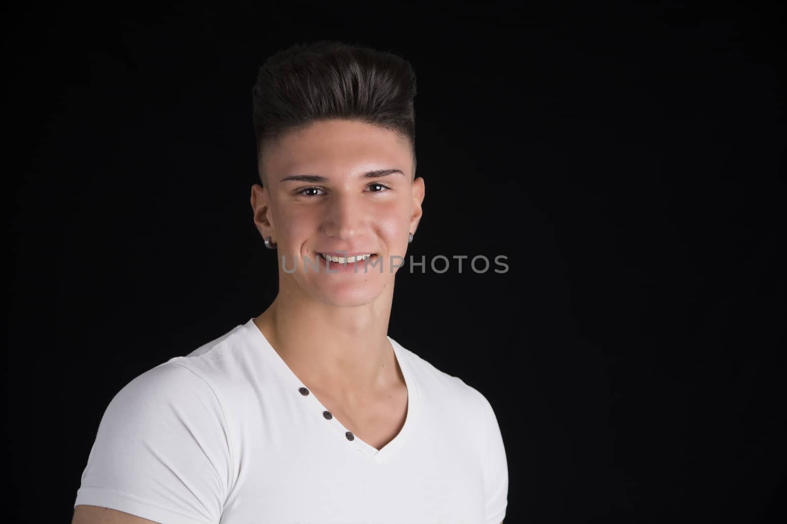 Head and shoulders portrait of smiling handsome young man on black background
