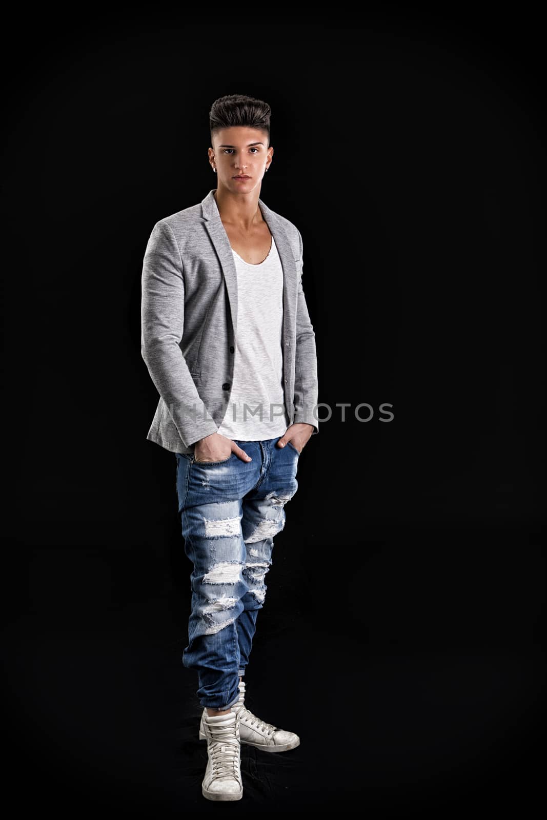Attractive trendy young man standing on black background by artofphoto